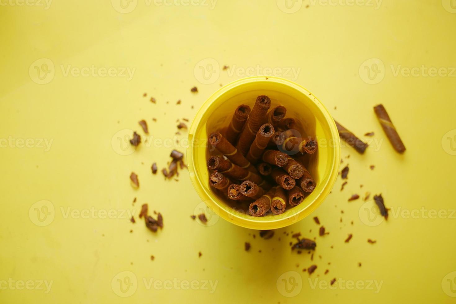 Waffelröllchenschokolade mit Mangogeschmack in Plastikbehälter auf gelbem Hintergrund foto