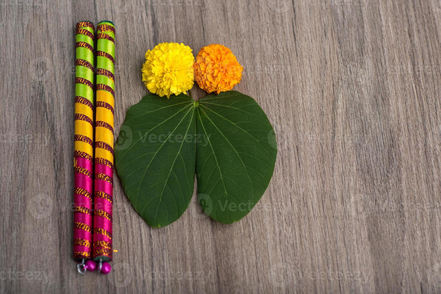 indisches Festival Dussehra und Navratri, mit goldenem Blatt Bauhinia Racemosa und Ringelblumen mit Dandiya-Sticks auf einem hölzernen Hintergrund foto