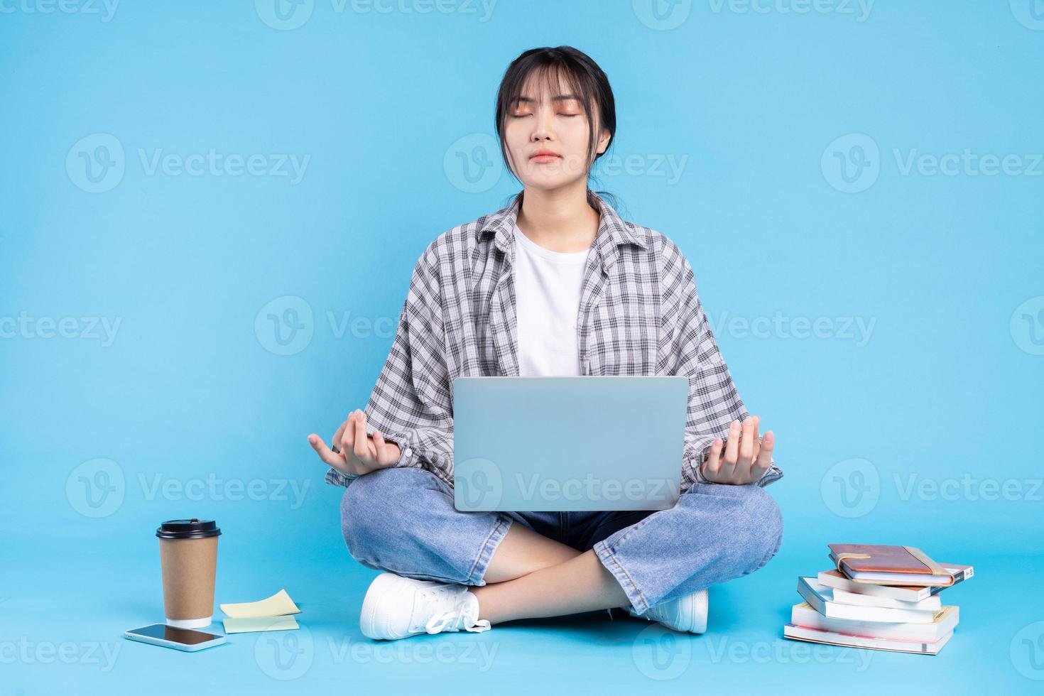 asiatische Studentin mit verspieltem Ausdruck auf blauem Hintergrund foto