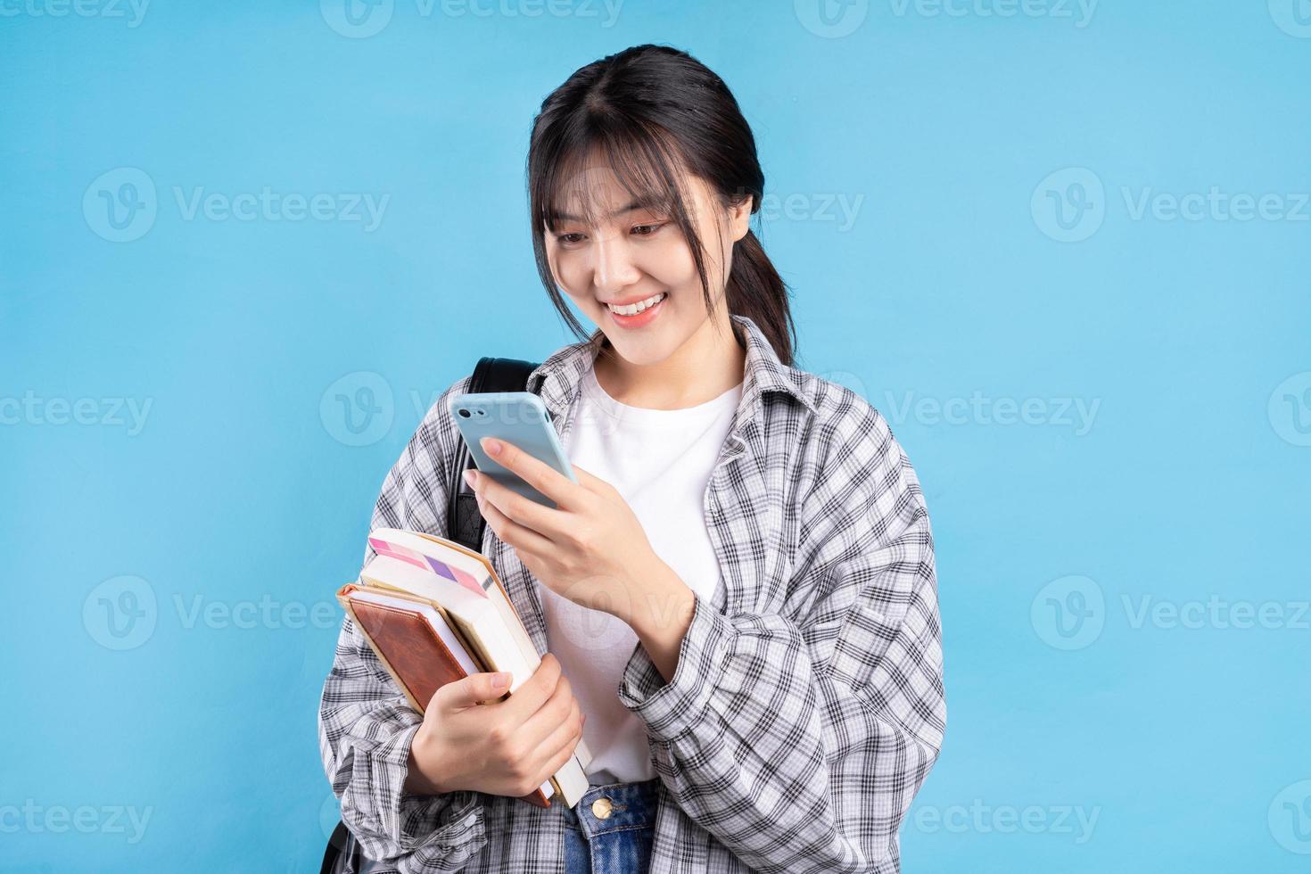 asiatische Studentin mit verspieltem Ausdruck auf blauem Hintergrund foto