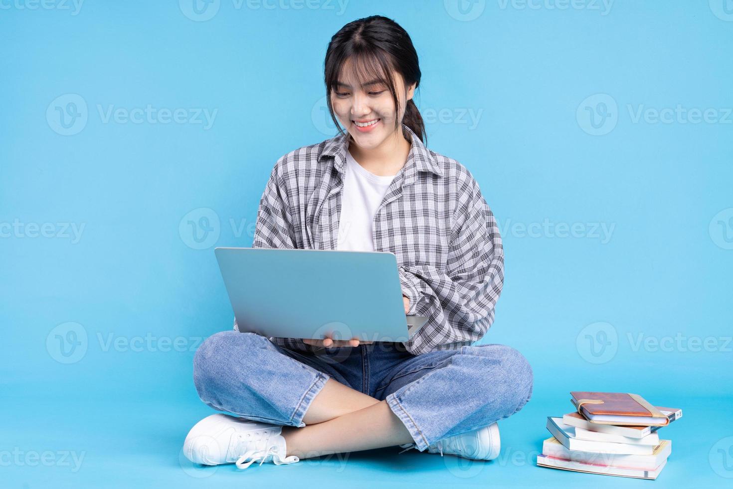 asiatische Studentin mit verspieltem Ausdruck auf blauem Hintergrund foto