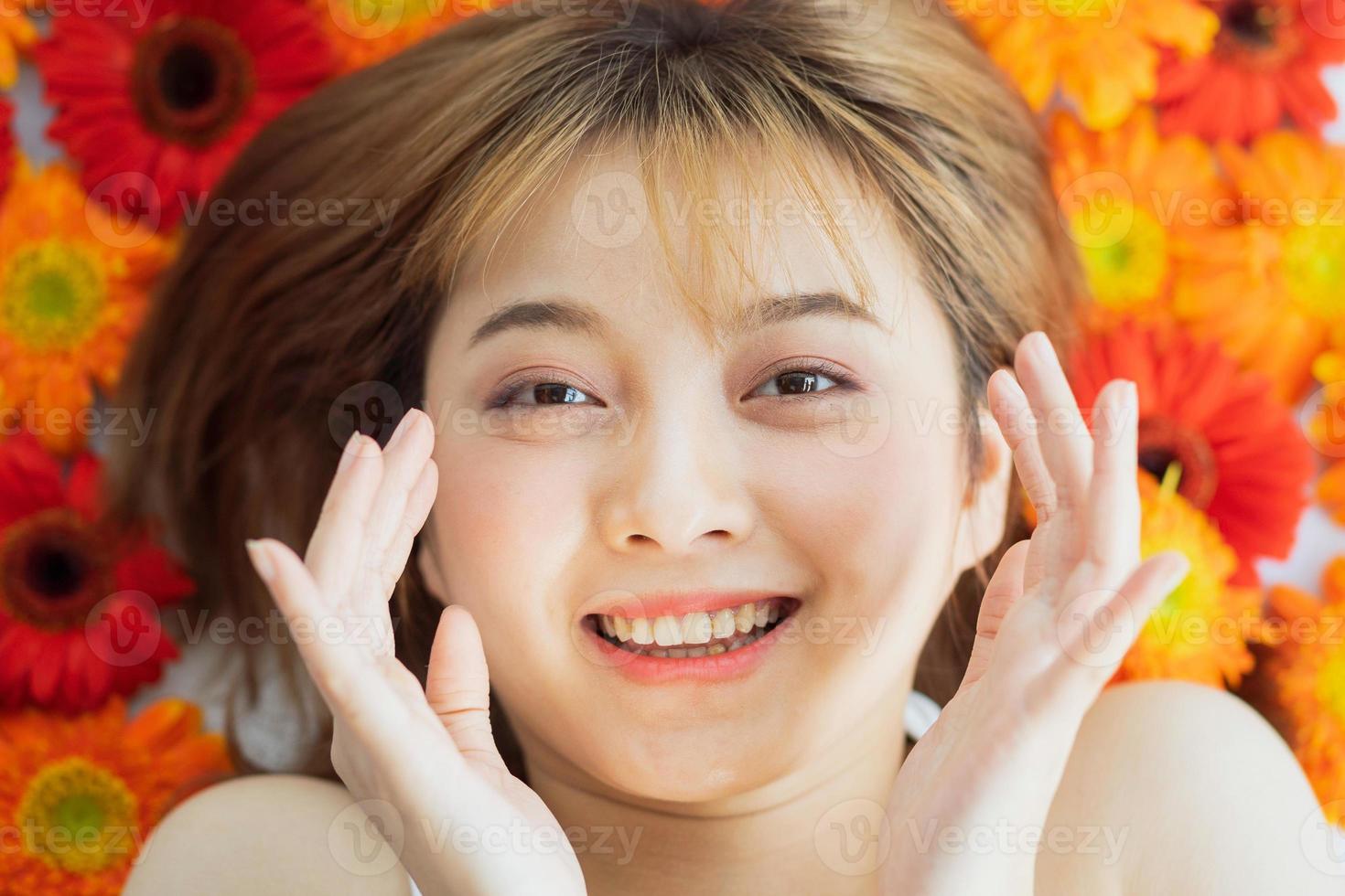 junges Mädchen, das auf einer Blume mit einem glücklichen Ausdruck liegt foto