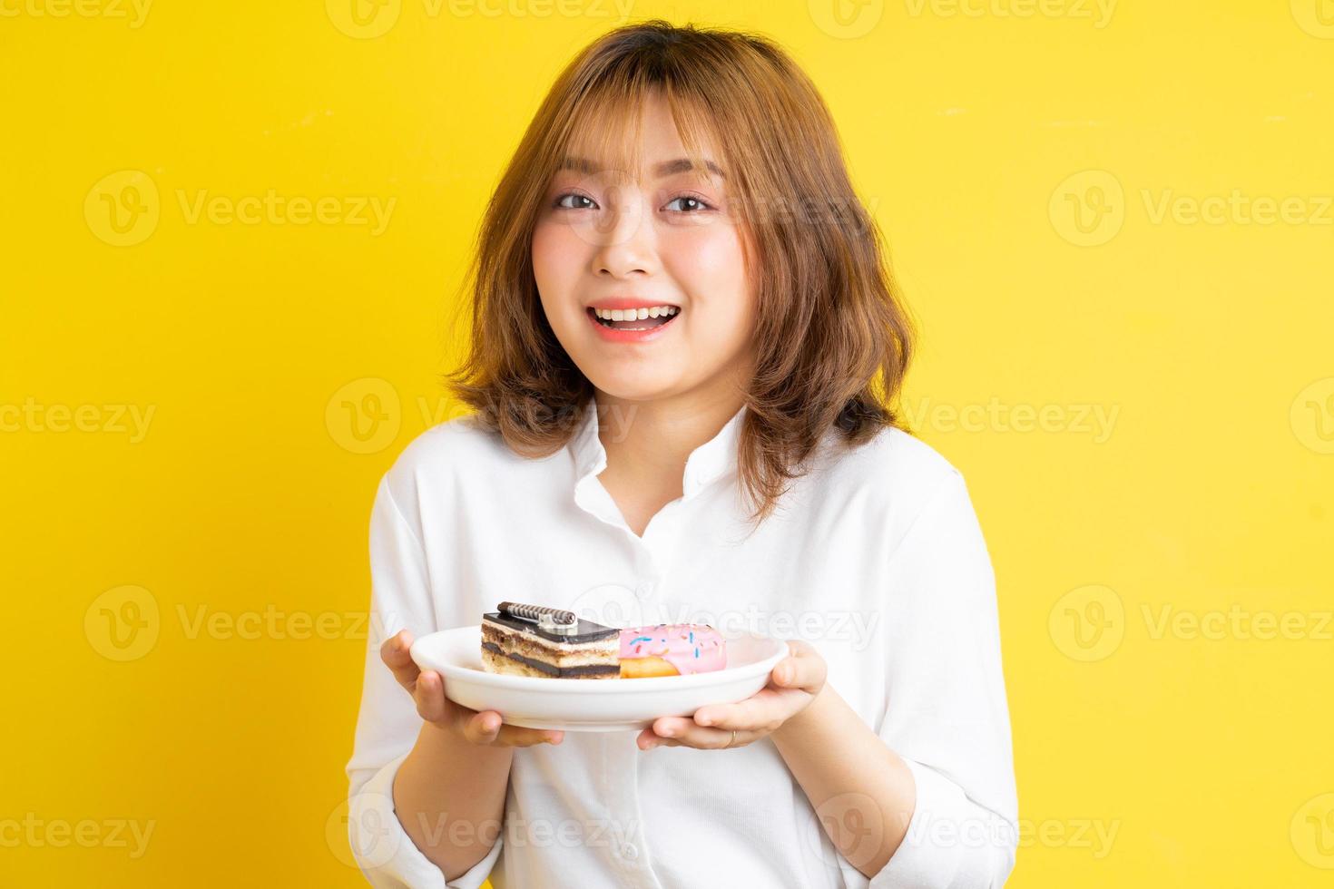 junges asiatisches Mädchen, das einen Teller Kuchen mit einem fröhlichen Ausdruck hält foto