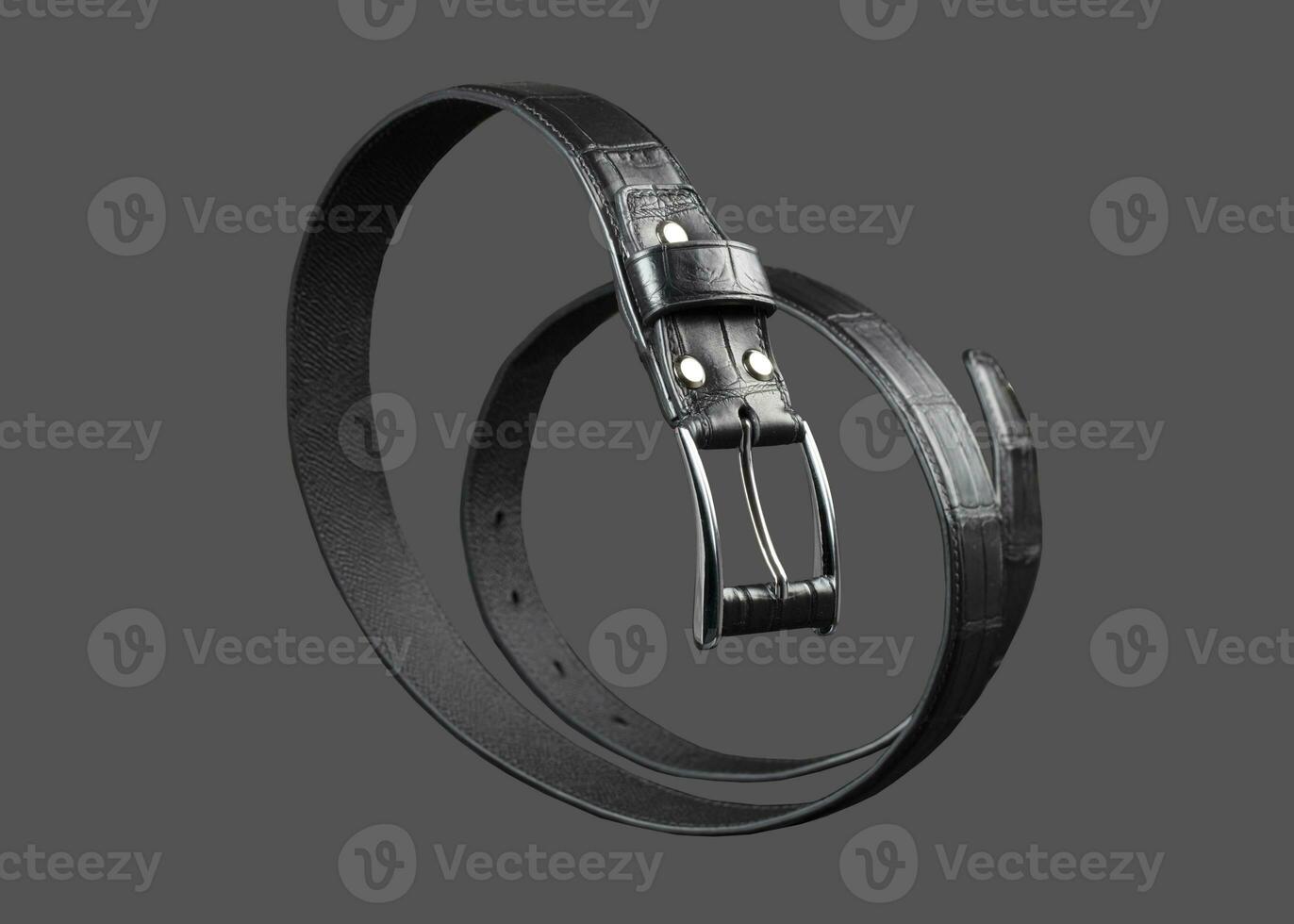 schwarz Leder Gürtel verdrehte im ein Spiral- auf ein grau Hintergrund. foto