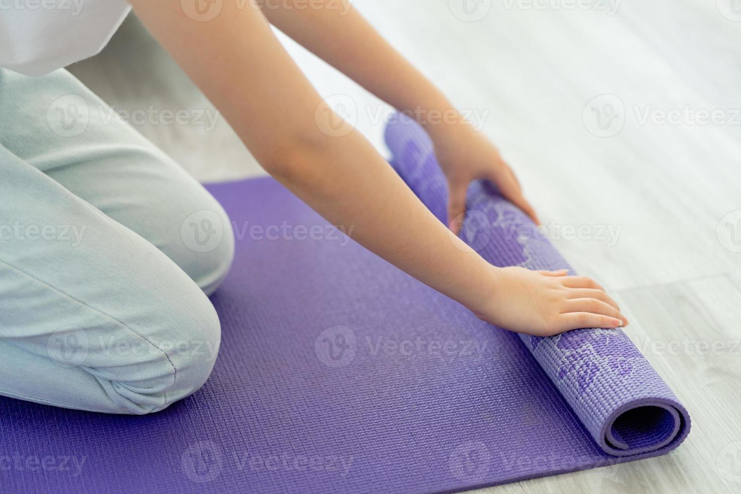 asiatische Frau, die Yogamatte ausbreitet, um Yoga zu Hause vorzubereiten foto