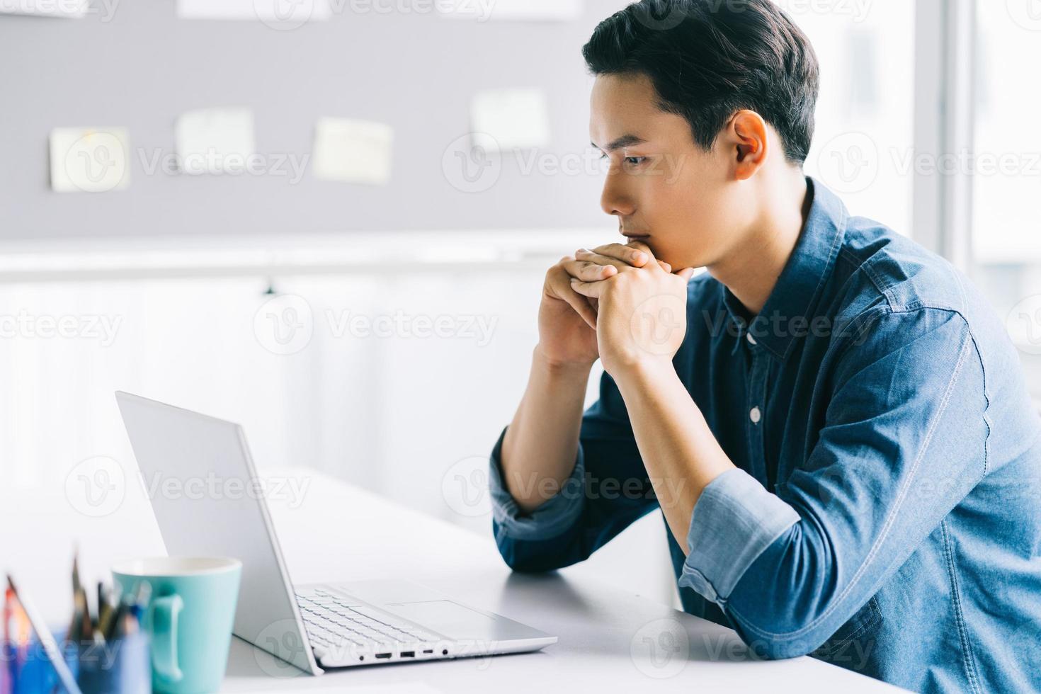 der asiatische mann konzentrierte sich auf seinen computerbildschirm foto