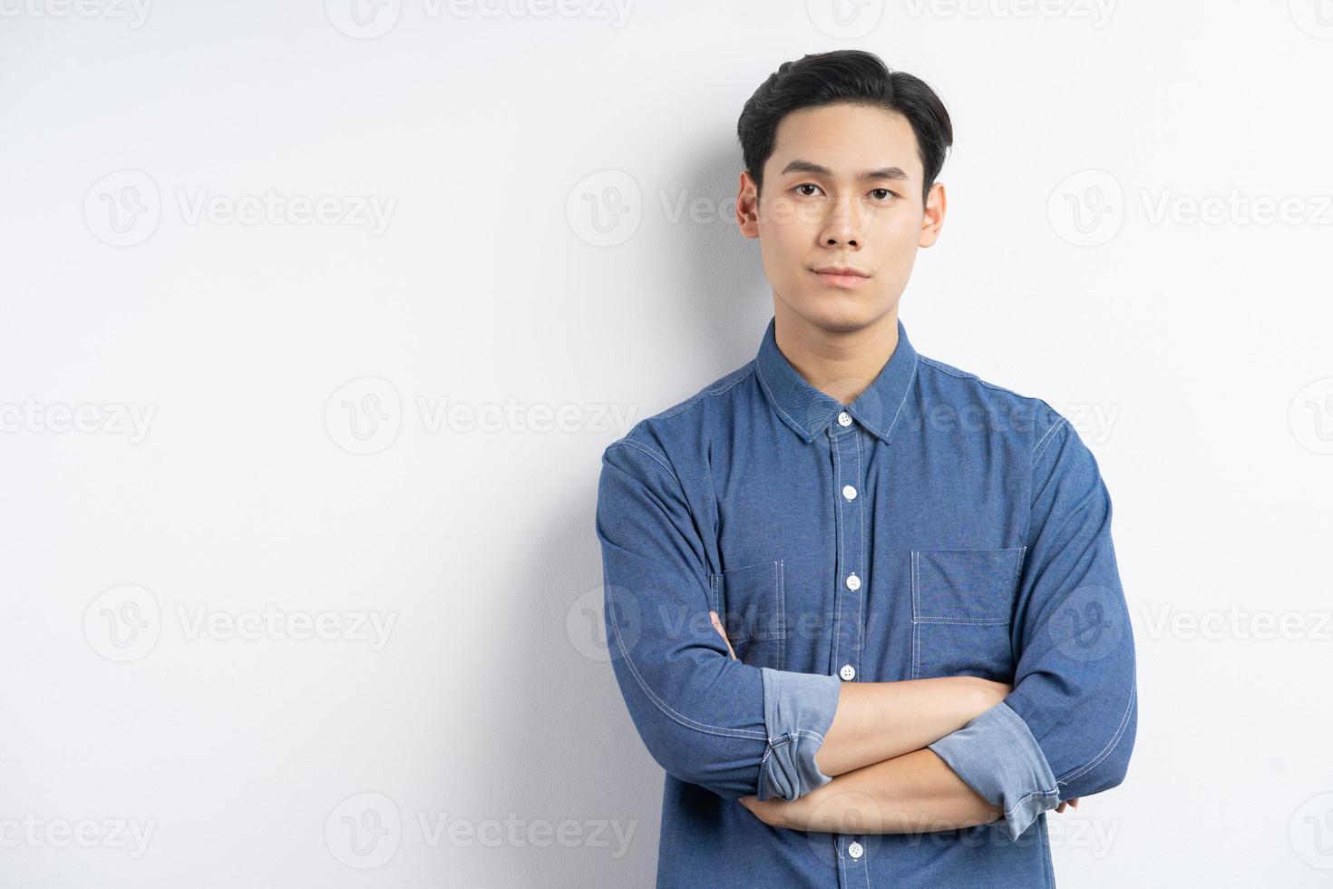 Foto eines asiatischen Geschäftsmannes, der mit verschränkten Armen steht und auf weißem Hintergrund lächelt