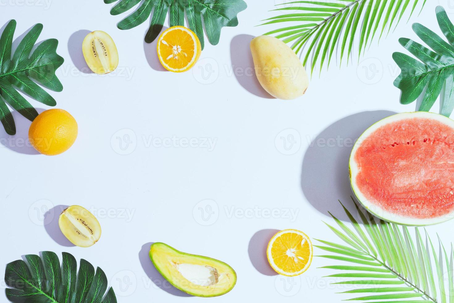 tropische Früchte wie Mango, Orange, Wassermelone, Avocado sind auf weißem Hintergrund angeordnet foto