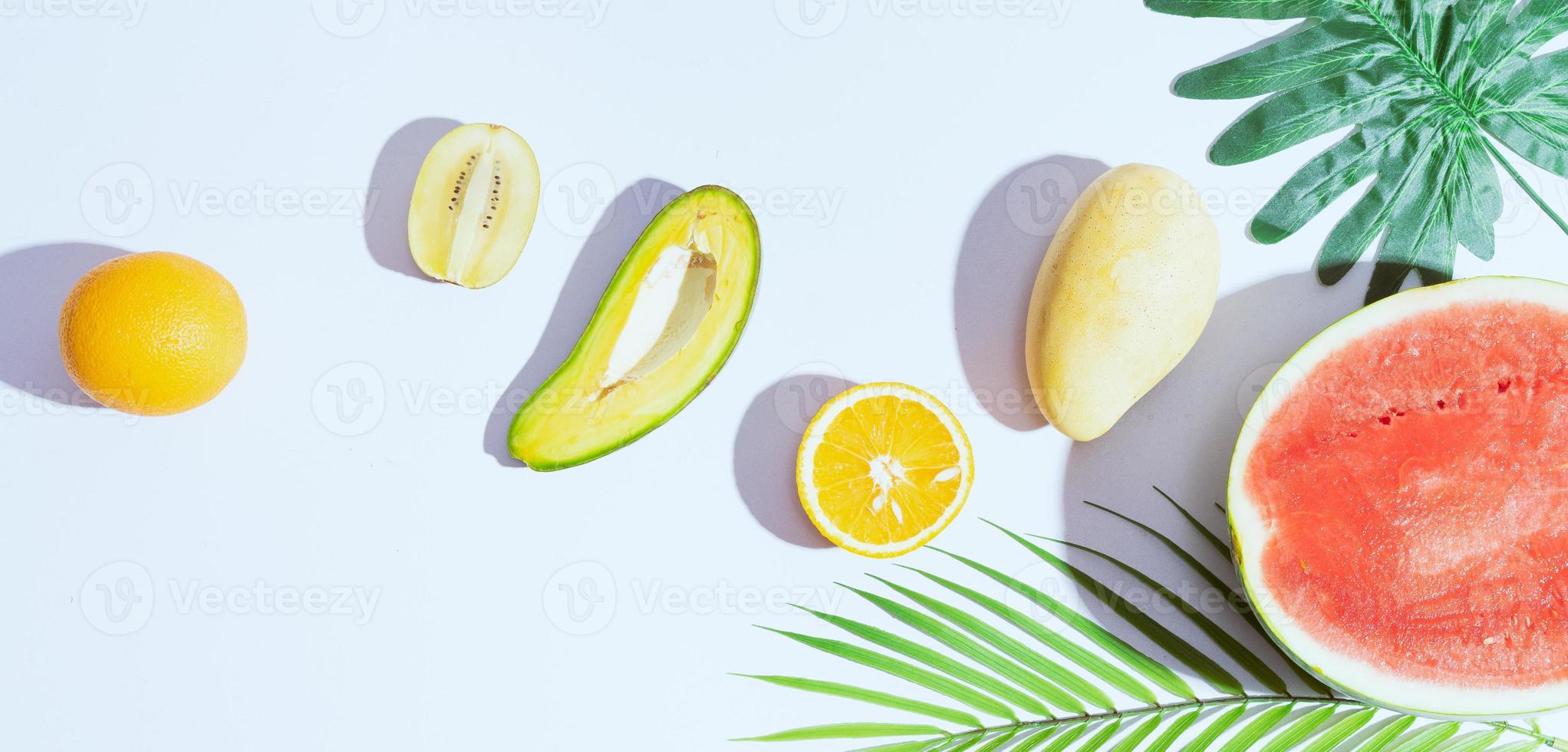 tropische Früchte wie Mango, Orange, Wassermelone, Avocado sind auf weißem Hintergrund angeordnet foto