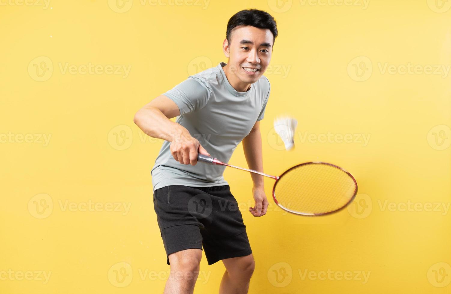 asiatischer Mann, der Badminton auf gelbem Hintergrund spielt foto
