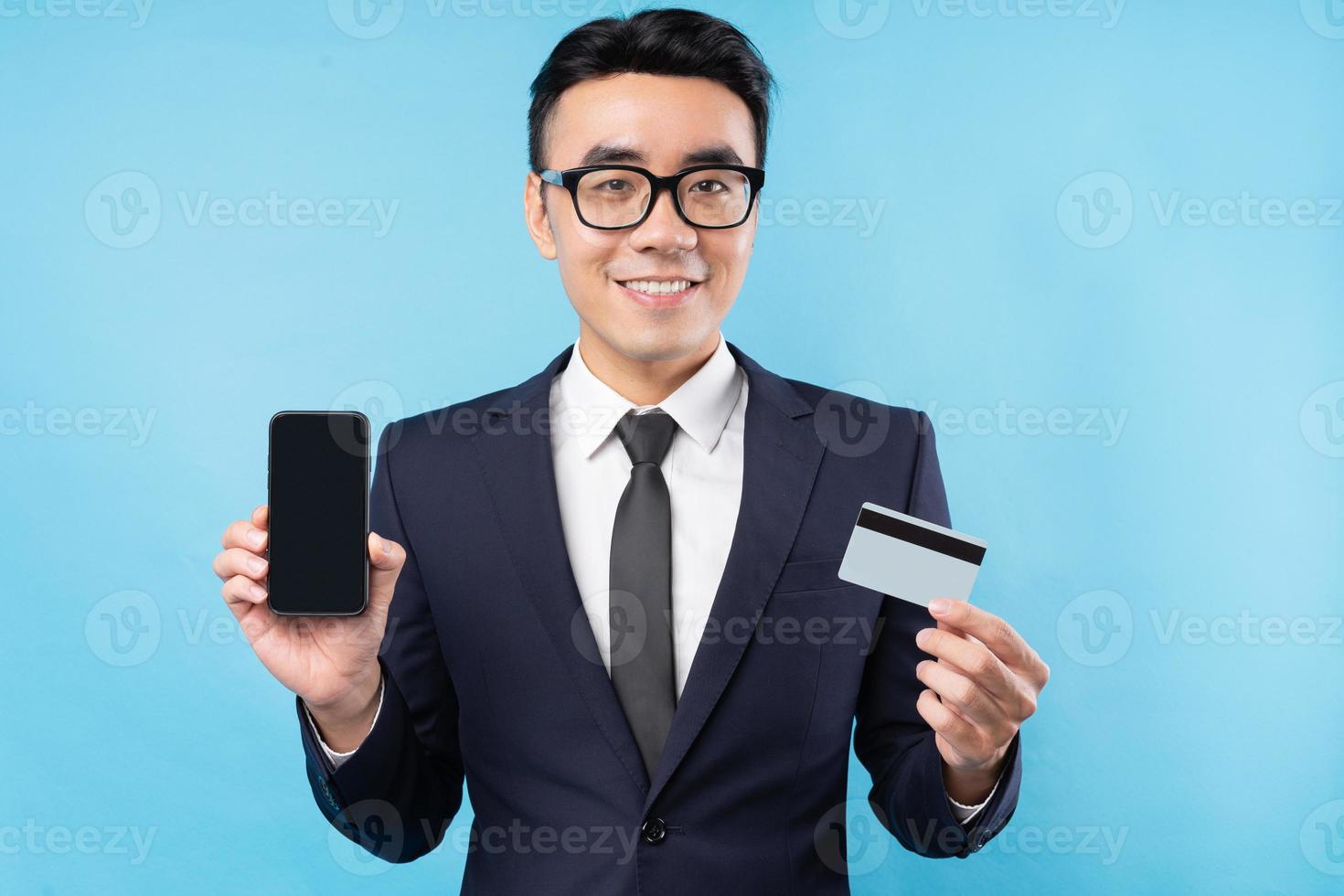 Asiatischer Geschäftsmann im Anzug mit Smartphone und Bankkarte foto