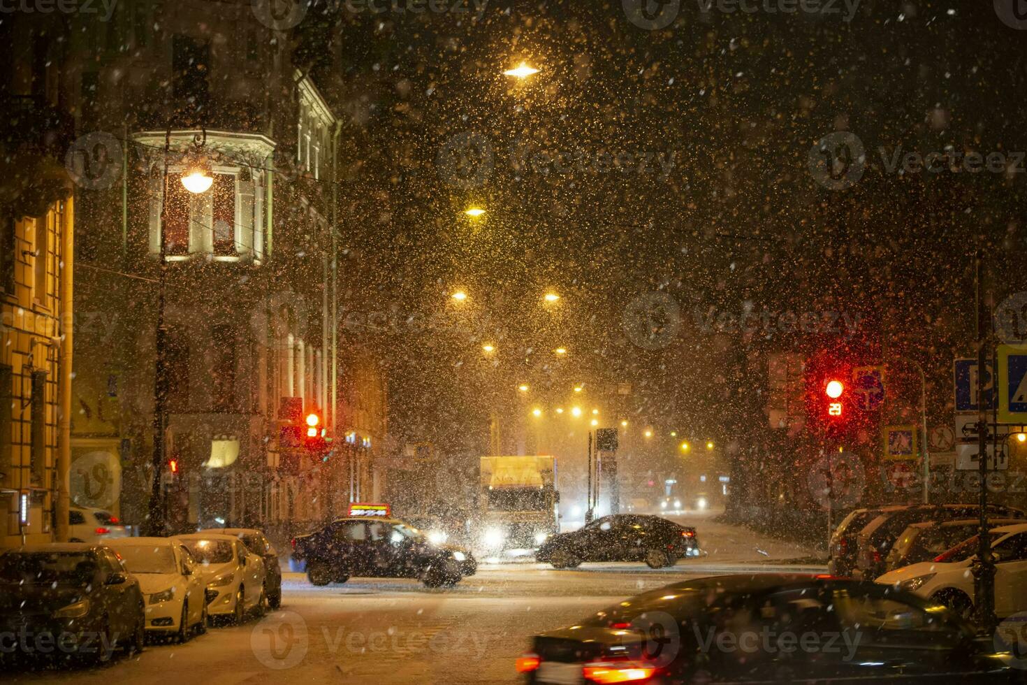 schneebedeckt Hintergrund von das Nacht Stadt mit der Verkehr Beleuchtung und Autos. foto