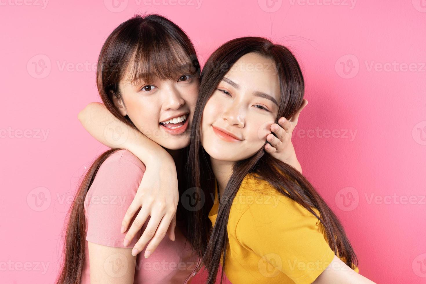 Porträt von zwei schönen jungen asiatischen Mädchen, die auf rosa Hintergrund posieren foto