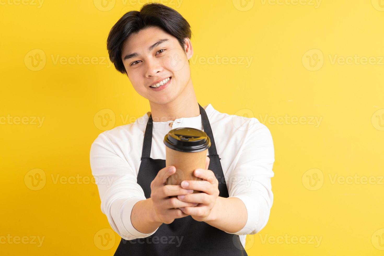 Porträt des männlichen Kellners mit Pappbecher in der Hand auf gelbem Hintergrund foto