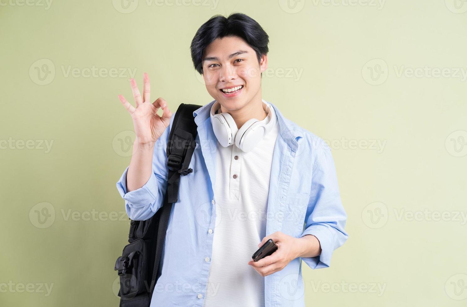 männlicher asiatischer Student, der in der Hand lächelt und ein gutes Symbol erstellt foto