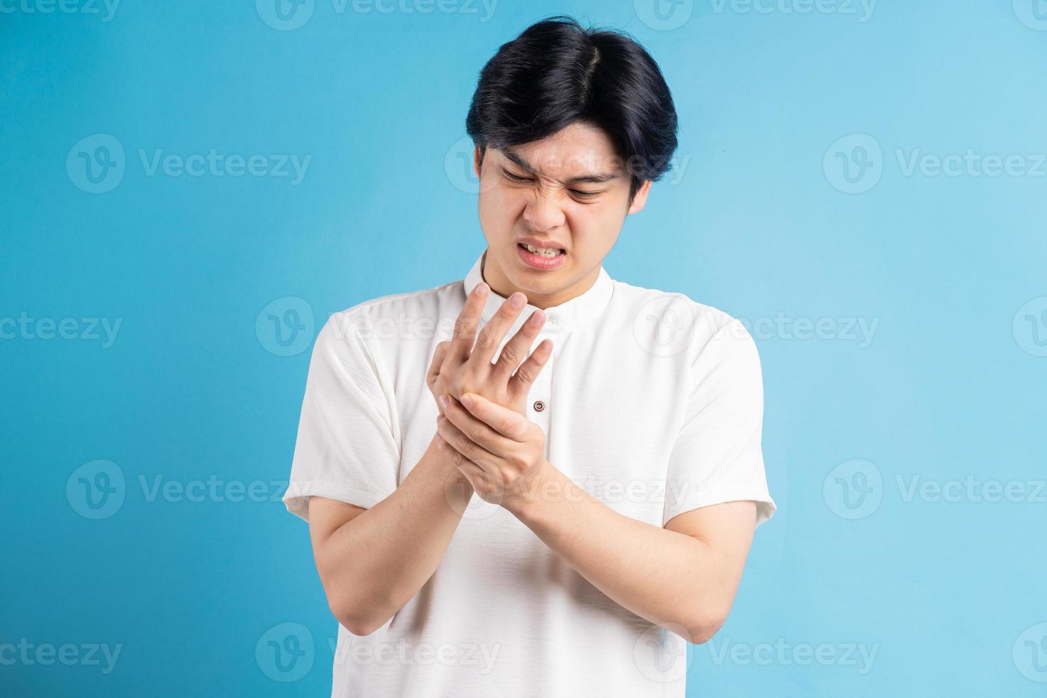 der asiatische mann ist verärgert über den schmerz in seiner handfläche foto