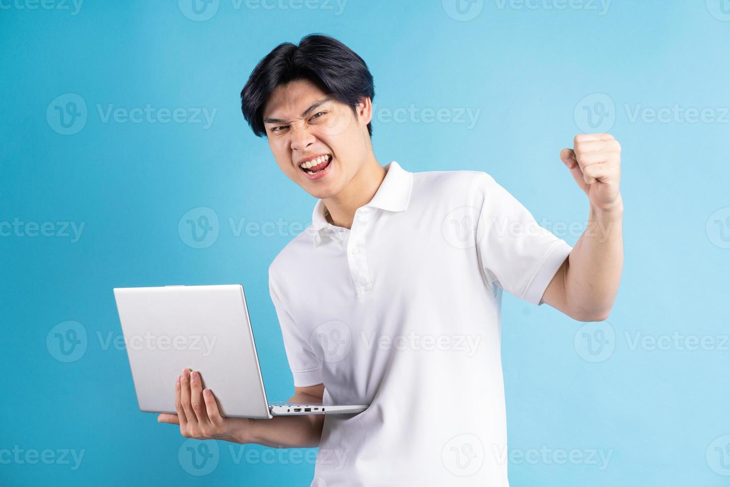 Der asiatische Mann hielt seinen Laptop in der Hand und zeigte einen triumphierenden Gesichtsausdruck foto