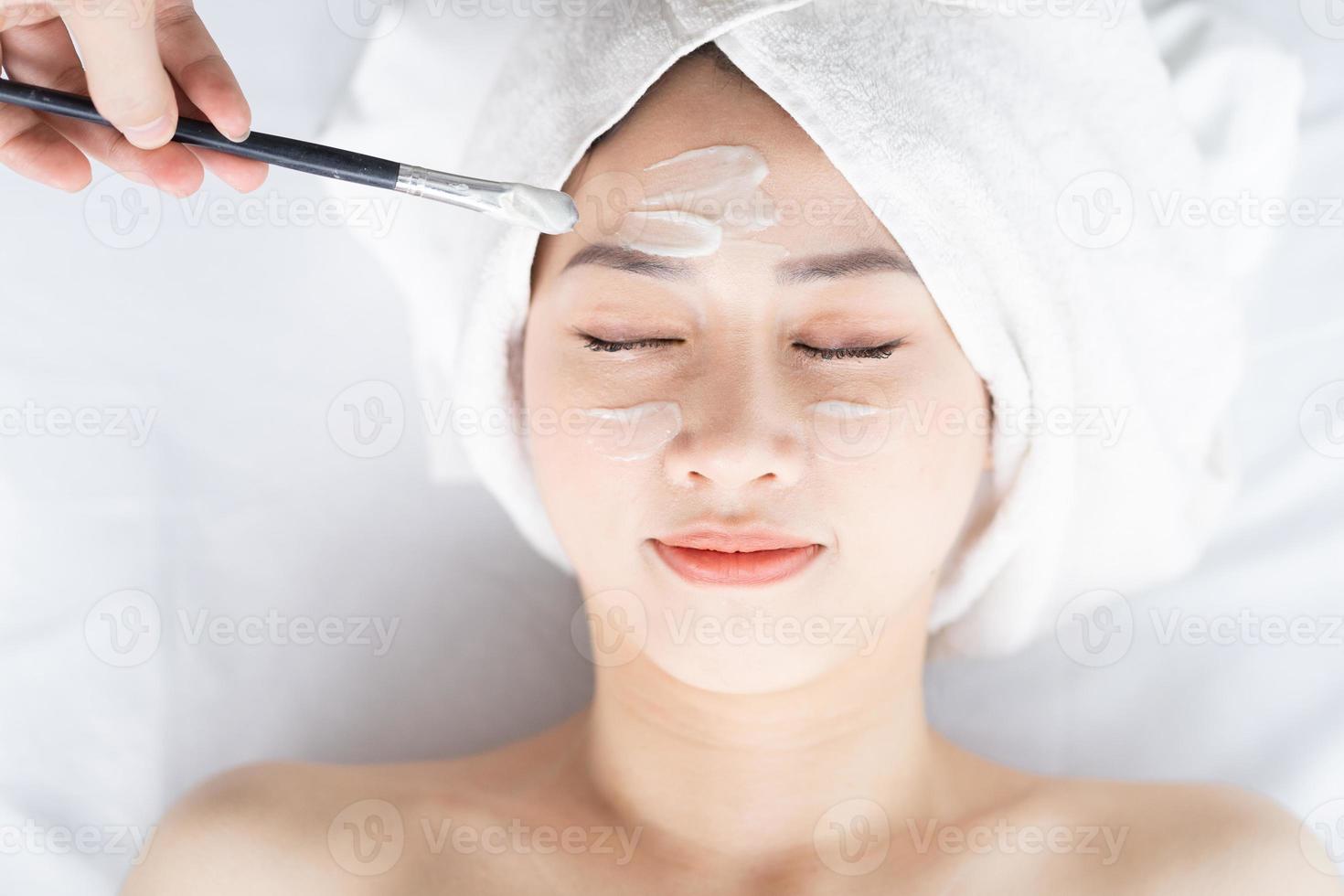 Asiatische Frau, die Schönheitsbehandlungen, Spa-Behandlungen und Cremes im Gesicht macht foto