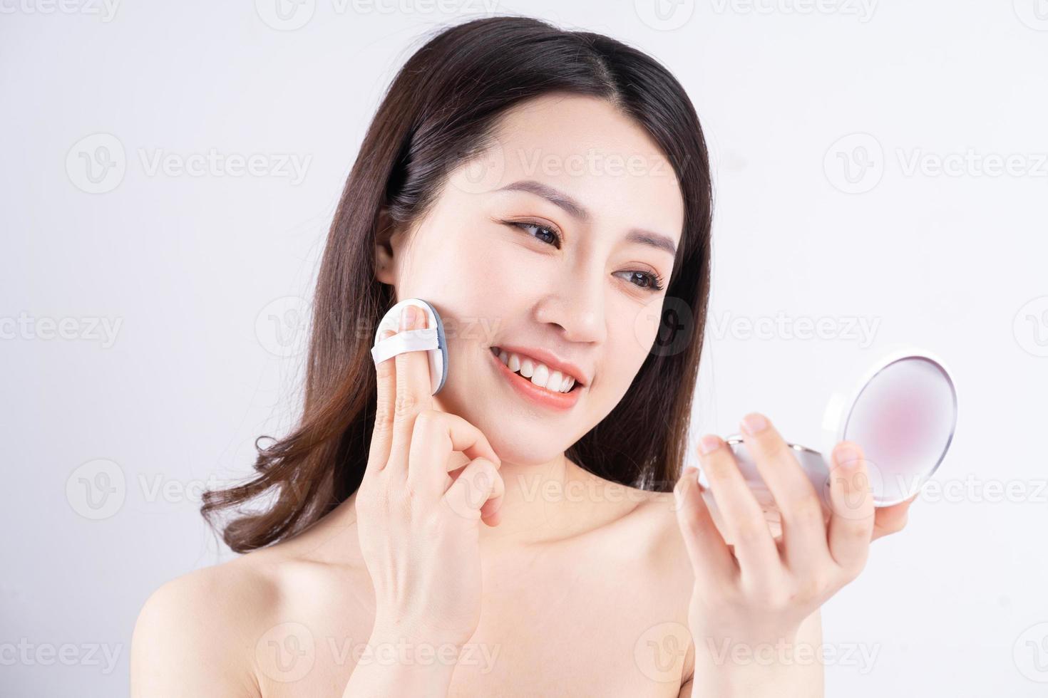 Junges asiatisches Mädchen, das mit einem glücklichen Gesicht eine Schachtel Make-up hält foto