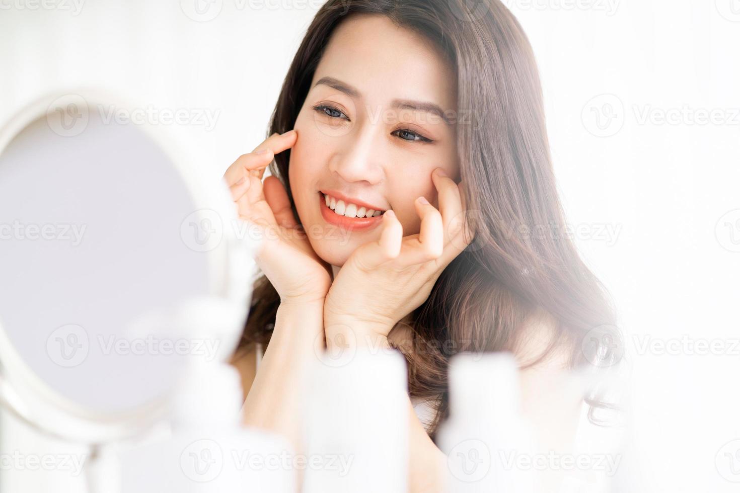 asiatische Frau sitzt Make-up vor Spiegel foto