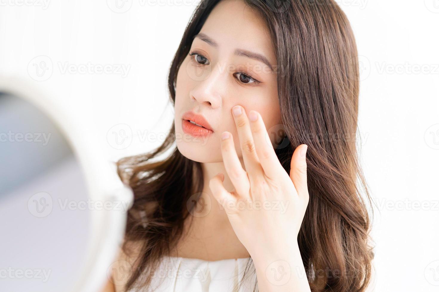 asiatische Frau sitzt Make-up vor Spiegel foto