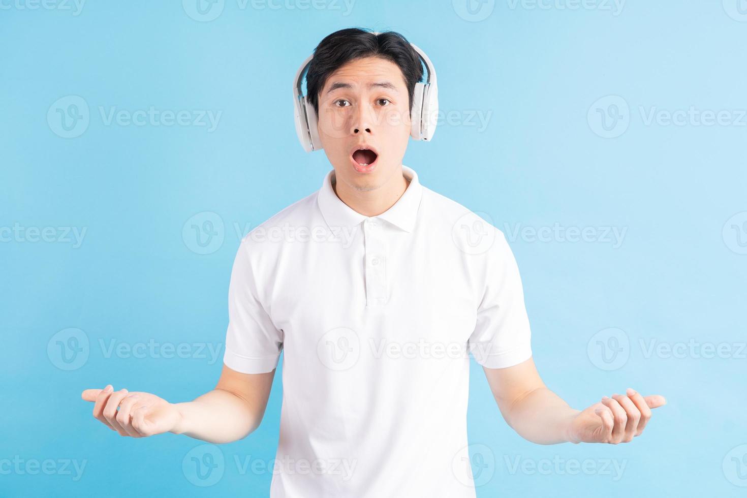ein Foto eines gutaussehenden asiatischen Mannes mit einem überraschten Ausdruck, der Musik hört