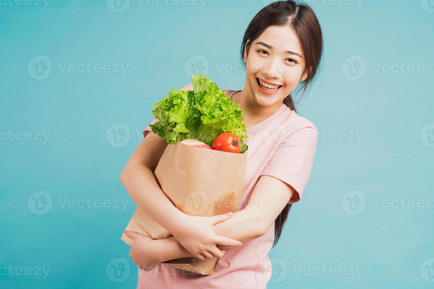 junges Mädchen, das eine Tüte mit frisch gekauftem Gemüse auf grünem Hintergrund hält foto