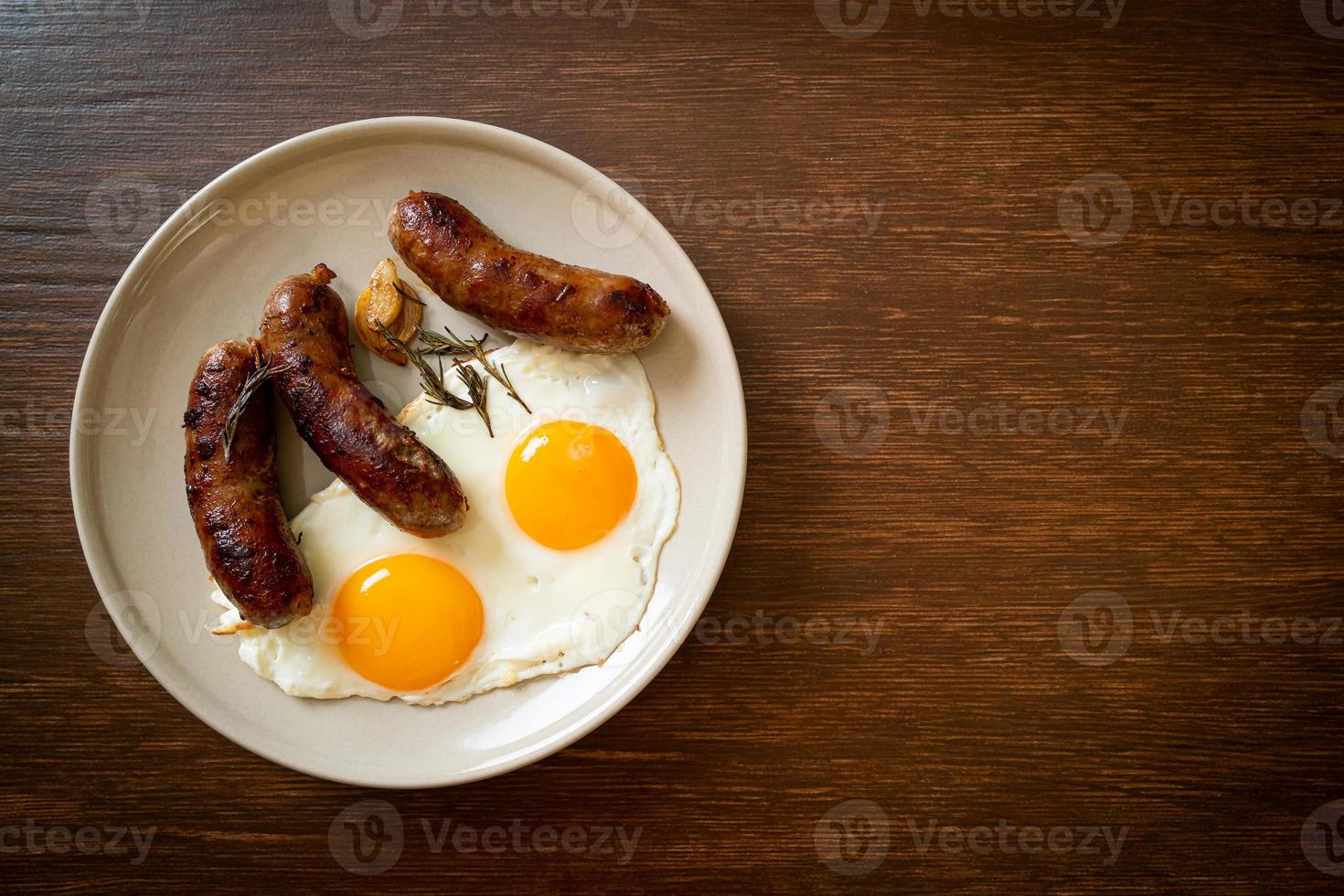 hausgemachtes doppeltes Spiegelei mit gebratener Schweinswurst - zum Frühstück foto