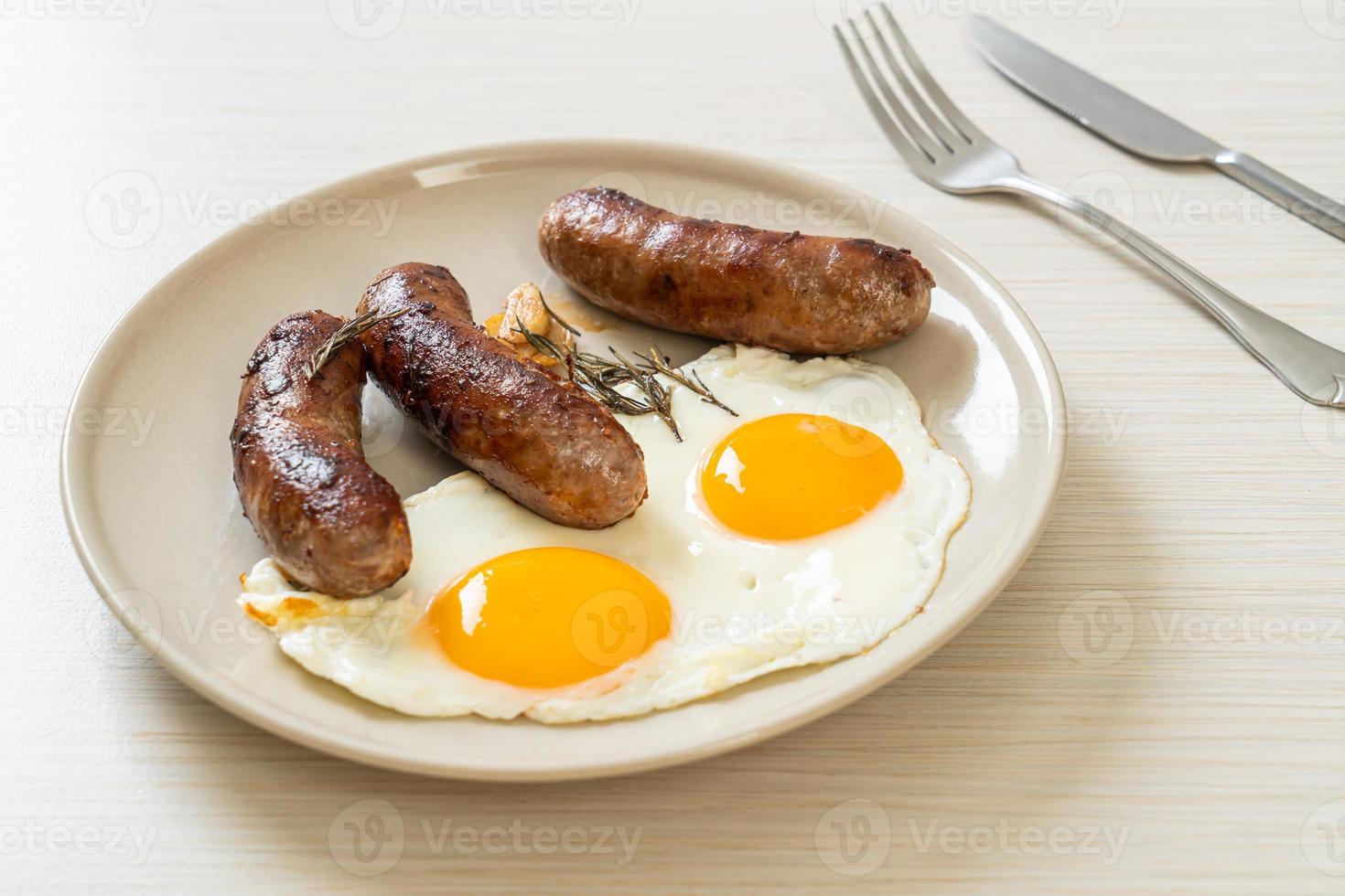 hausgemachtes doppeltes Spiegelei mit gebratener Schweinswurst - zum Frühstück foto