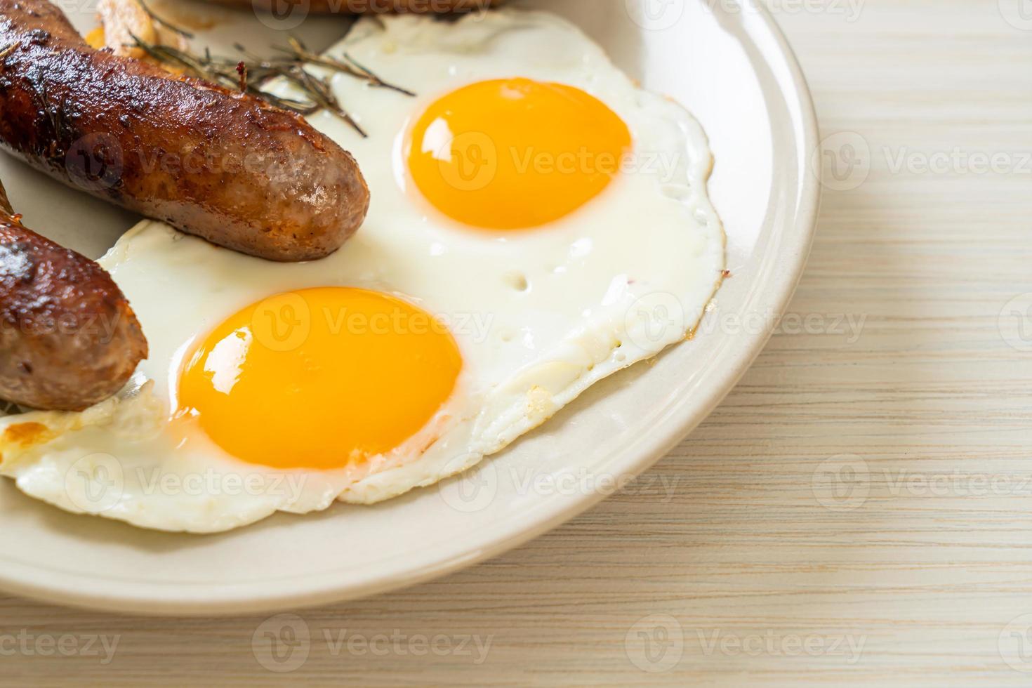 hausgemachtes doppeltes Spiegelei mit gebratener Schweinswurst - zum Frühstück foto