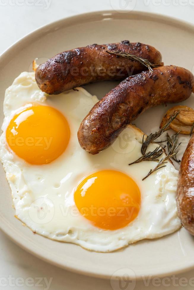 hausgemachtes doppeltes Spiegelei mit gebratener Schweinswurst - zum Frühstück foto