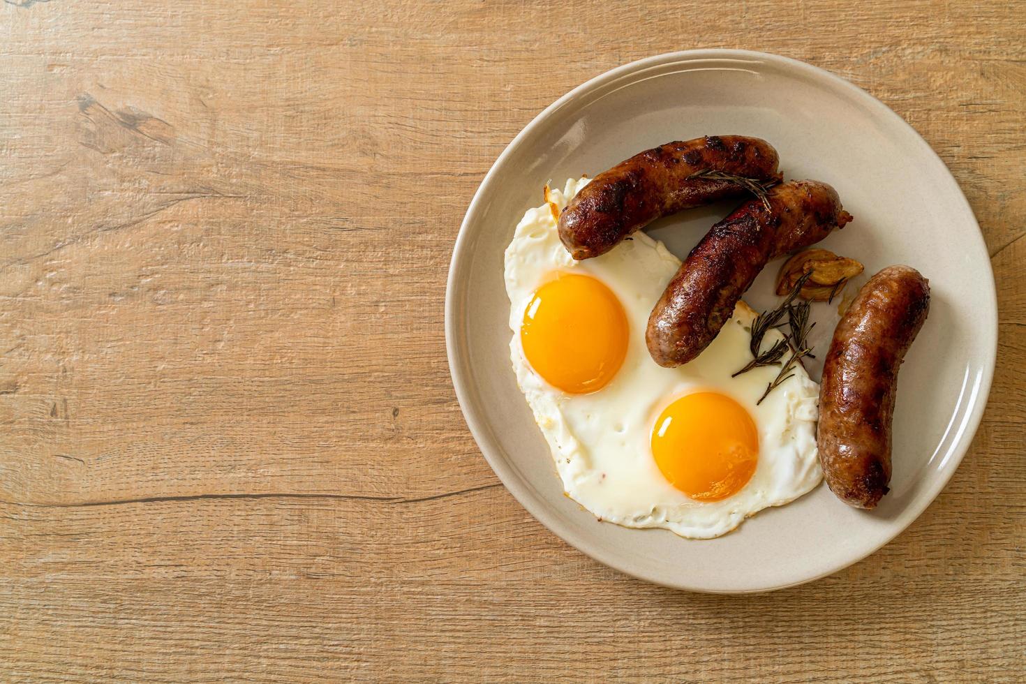 hausgemachtes doppeltes Spiegelei mit gebratener Schweinswurst - zum Frühstück foto