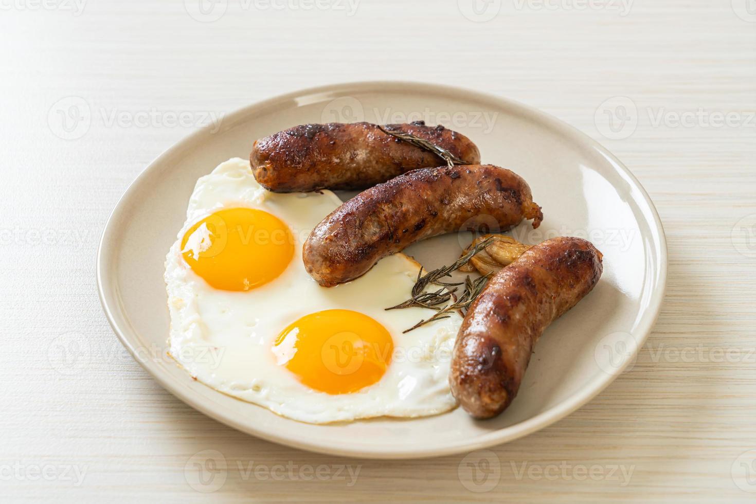 hausgemachtes doppeltes Spiegelei mit gebratener Schweinswurst - zum Frühstück foto