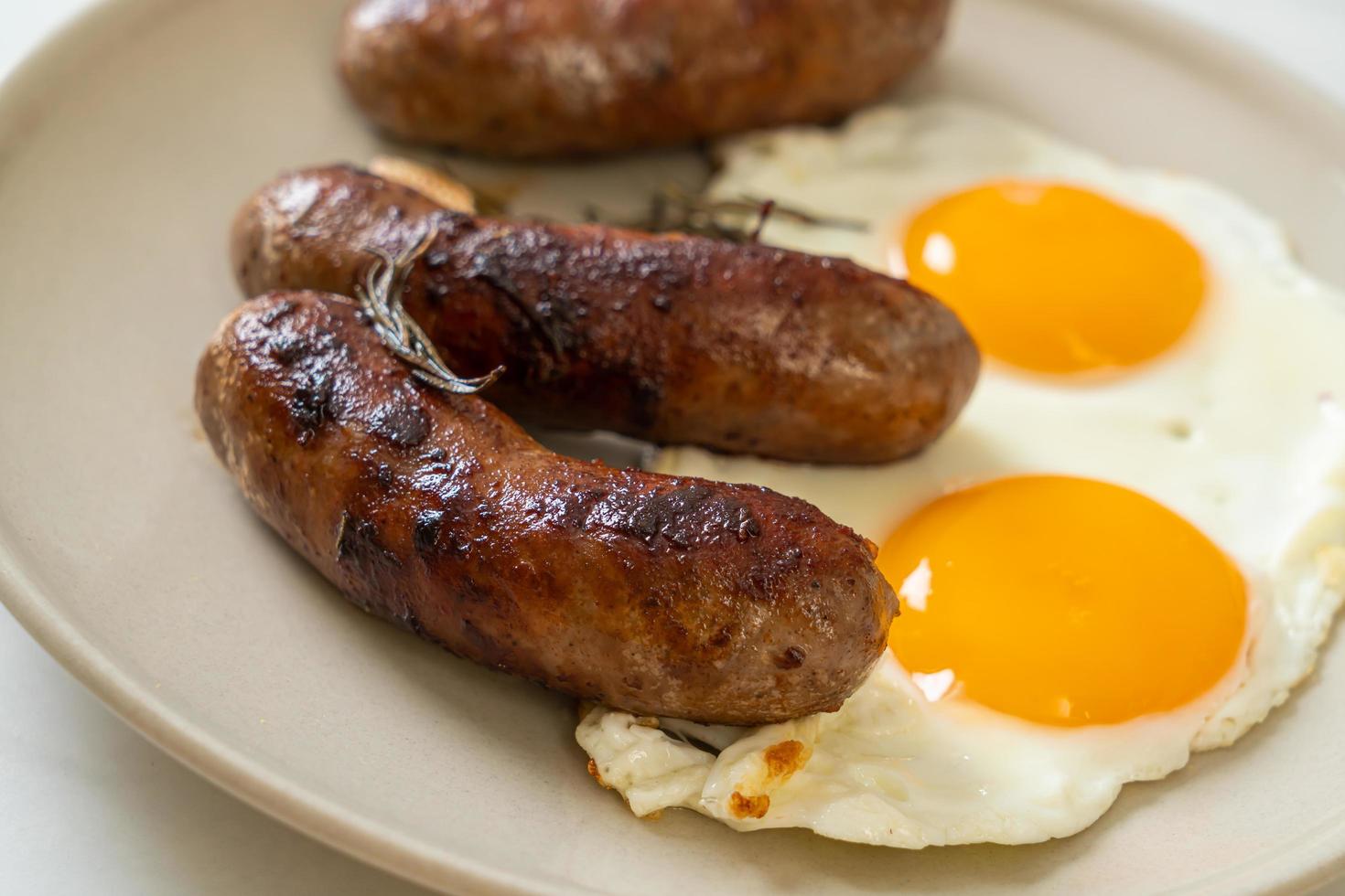 hausgemachtes doppeltes Spiegelei mit gebratener Schweinswurst - zum Frühstück foto