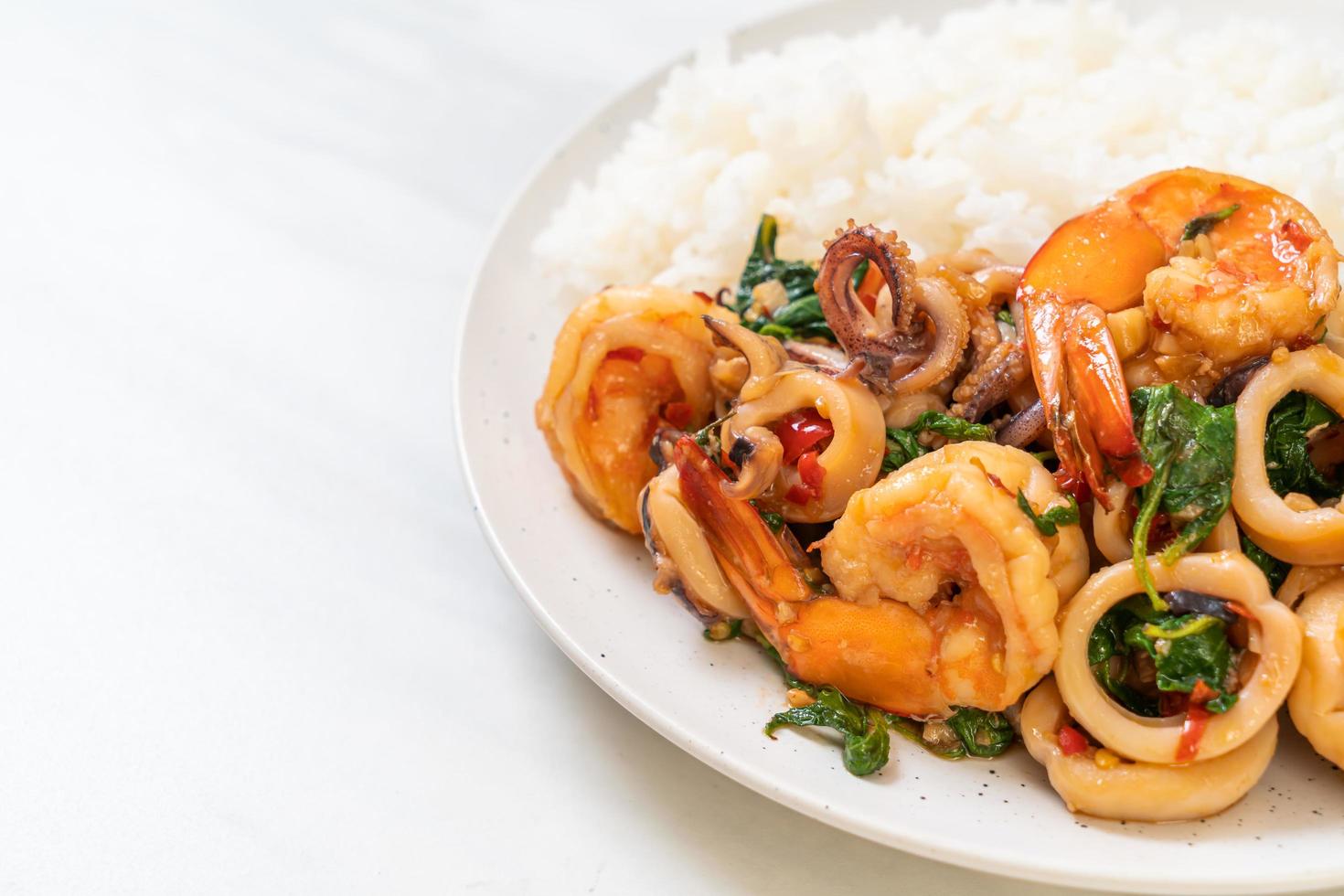 Reis und gebratene Meeresfrüchte von Garnelen und Tintenfisch mit thailändischem Basilikum - asiatische Küche foto