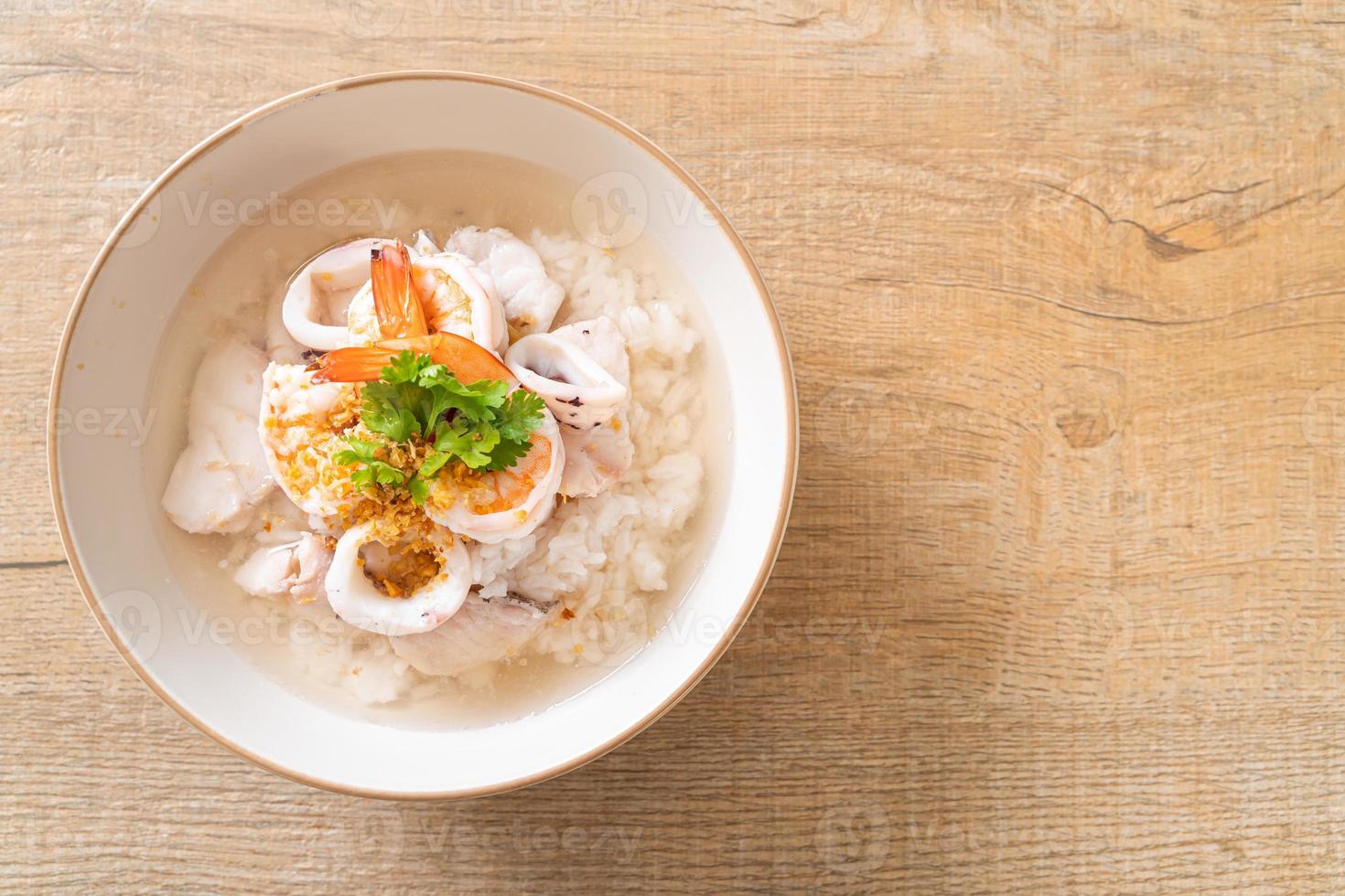 Porridge oder gekochte Reissuppe mit Meeresfrüchten von Garnelen, Tintenfisch und Fisch in einer Schüssel foto