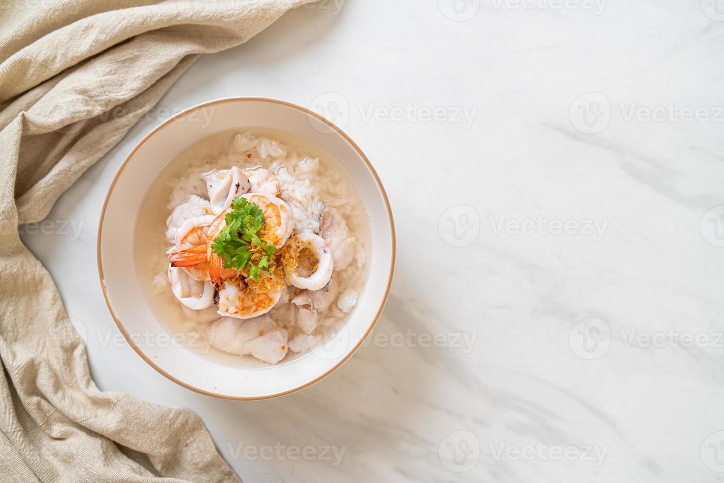 Porridge oder gekochte Reissuppe mit Meeresfrüchten von Garnelen, Tintenfisch und Fisch in einer Schüssel foto