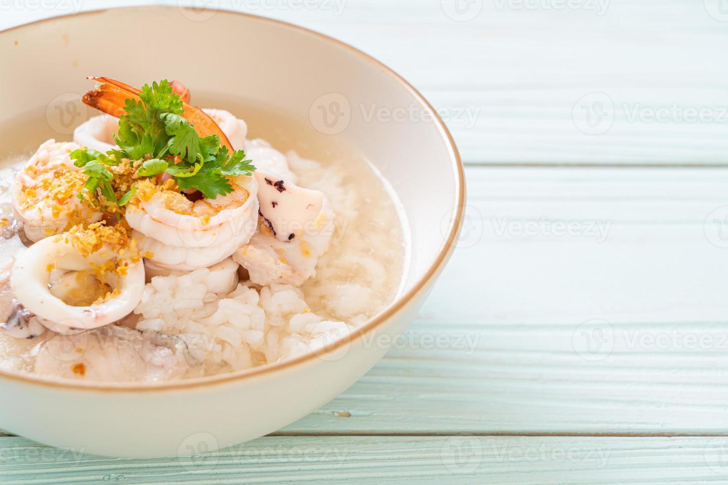 Porridge oder gekochte Reissuppe mit Meeresfrüchten von Garnelen, Tintenfisch und Fisch in einer Schüssel foto