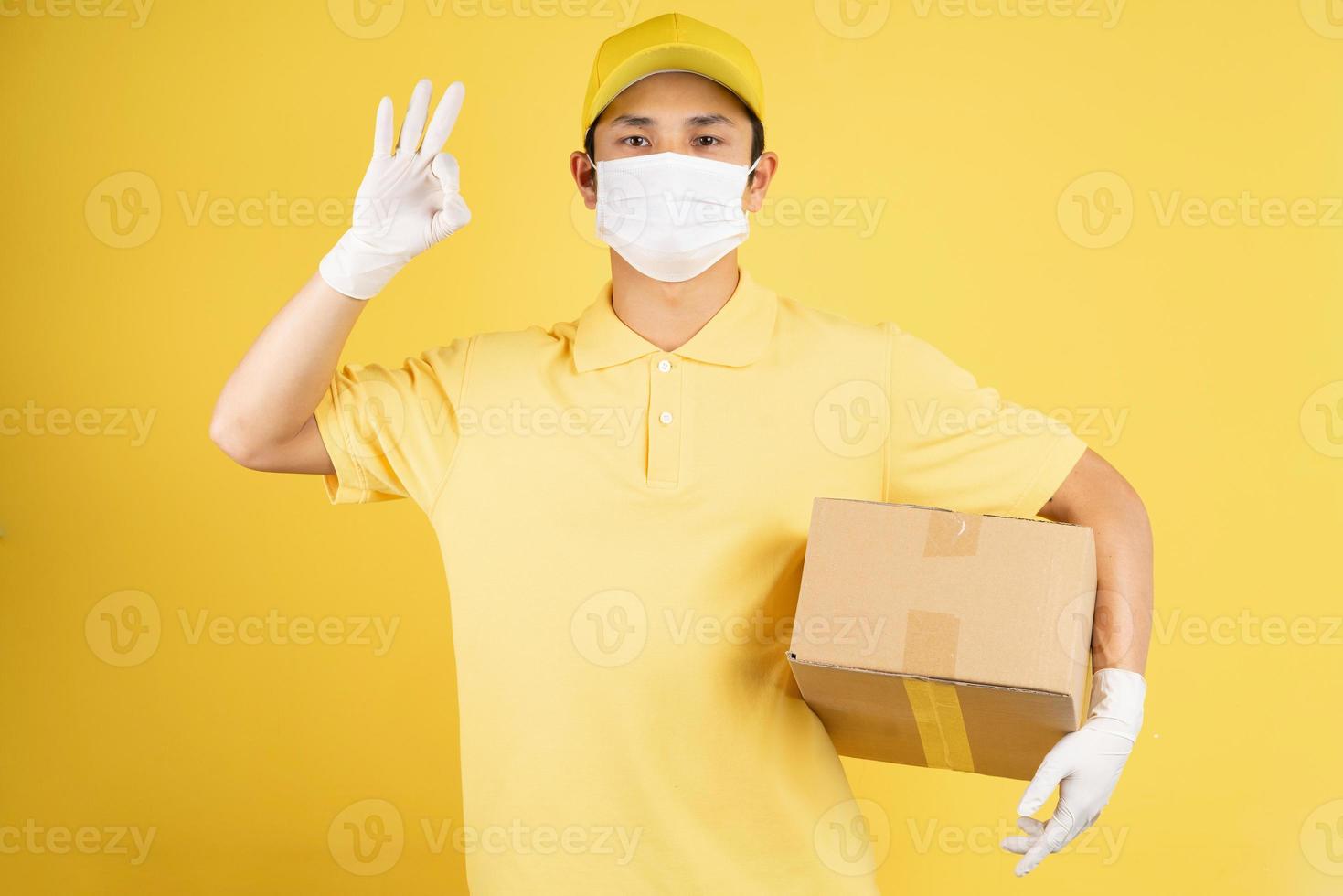 Porträt eines männlichen Lieferboten, der während der Epidemiezeit eine Maske im Hintergrund trägt foto