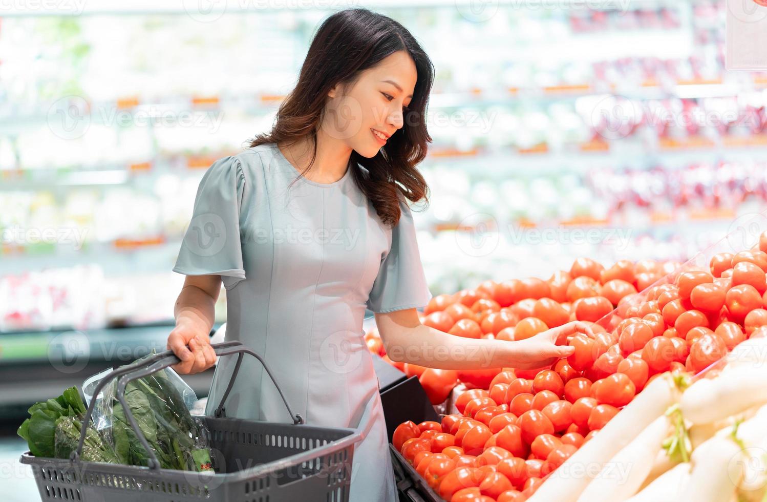 Das junge Mädchen entscheidet sich dafür, Gemüse im Supermarkt zu kaufen foto
