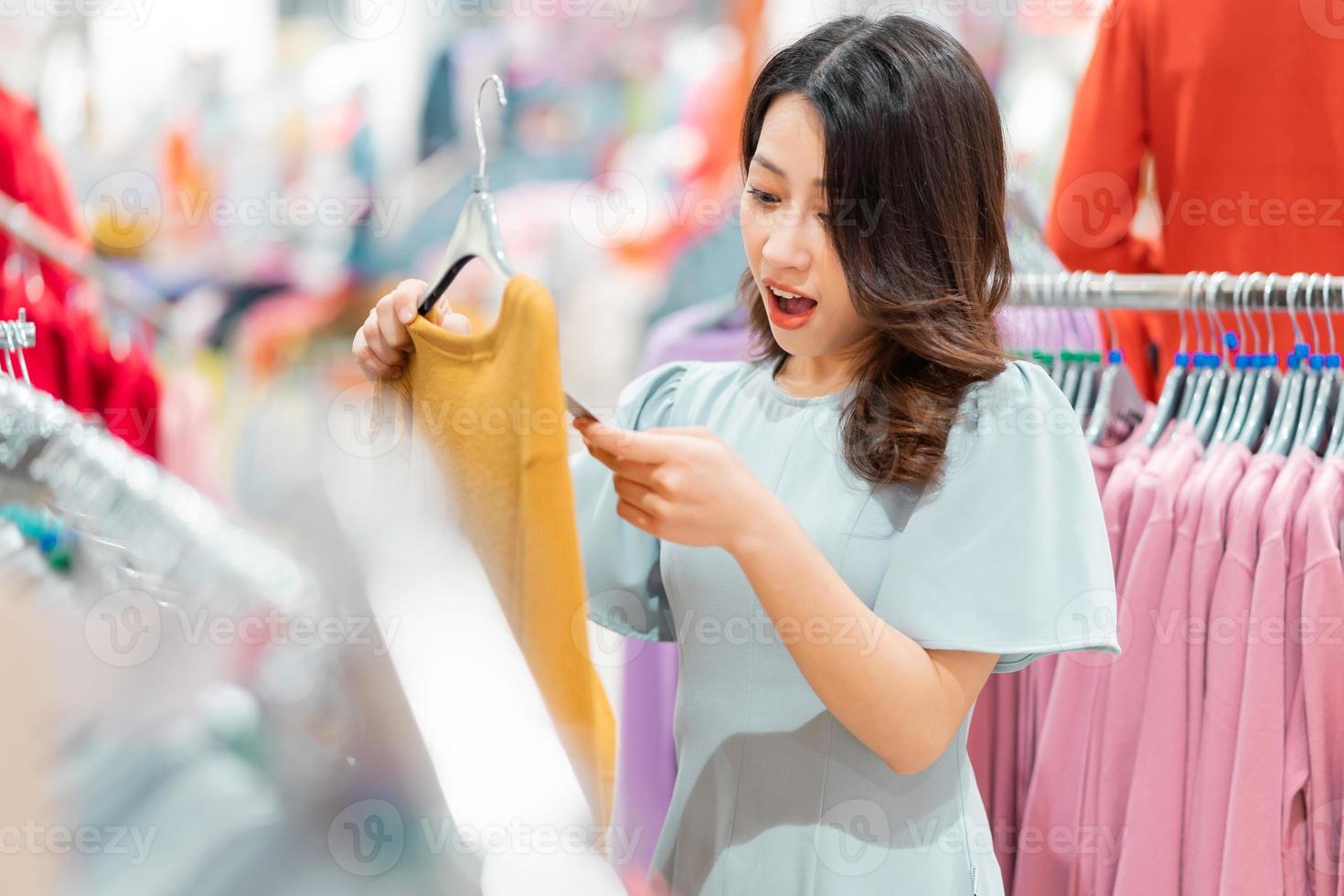 junges Mädchen entscheidet sich, Kleidung im Einkaufszentrum zu kaufen foto