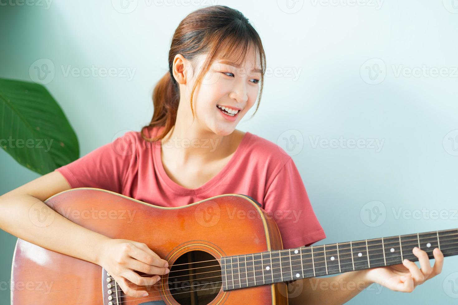 junge Asiatin, die zu Hause Gitarre lernt foto