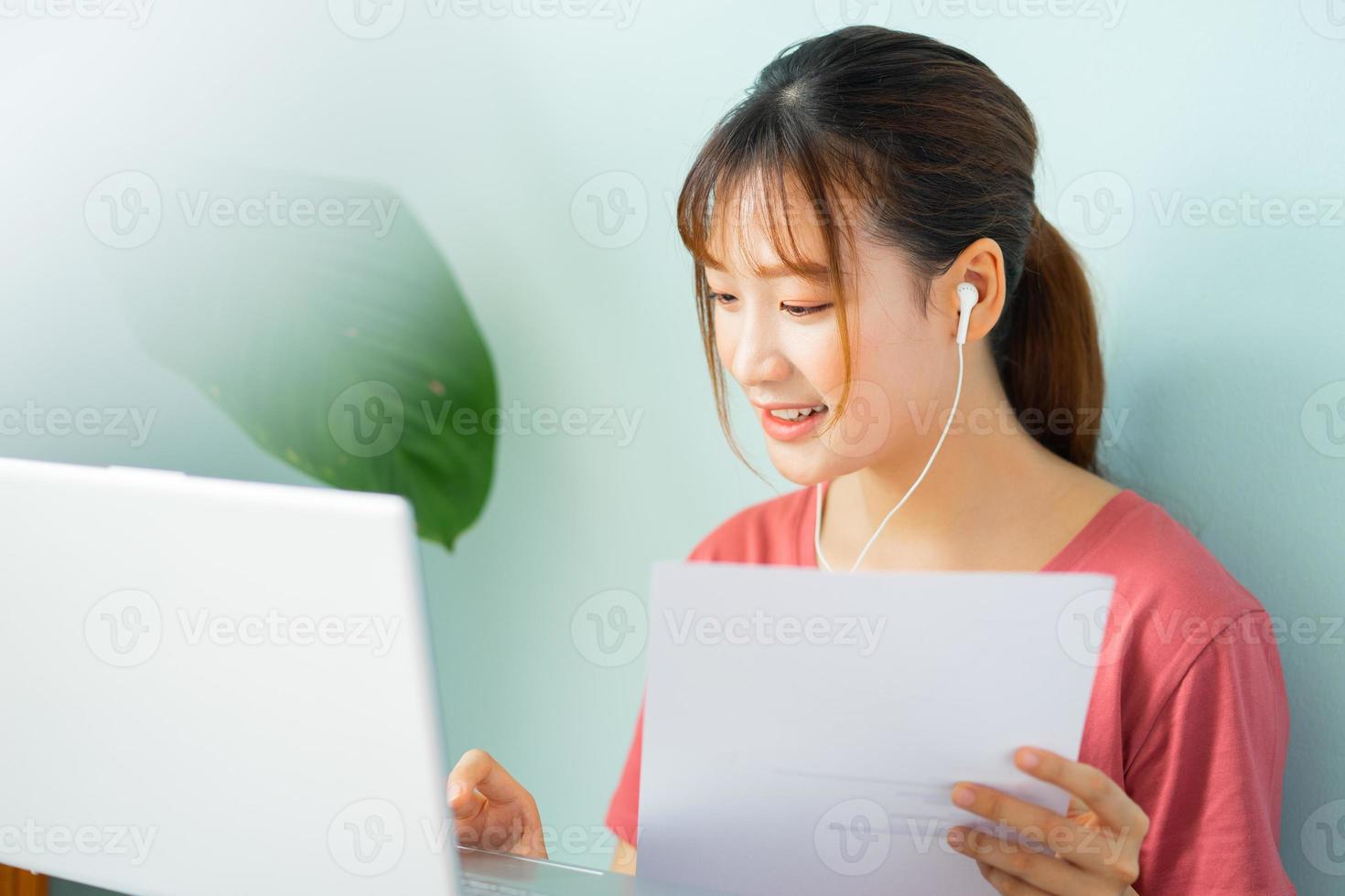 asiatische frau, die auf dem boden sitzt, während sie von zu hause arbeitet foto