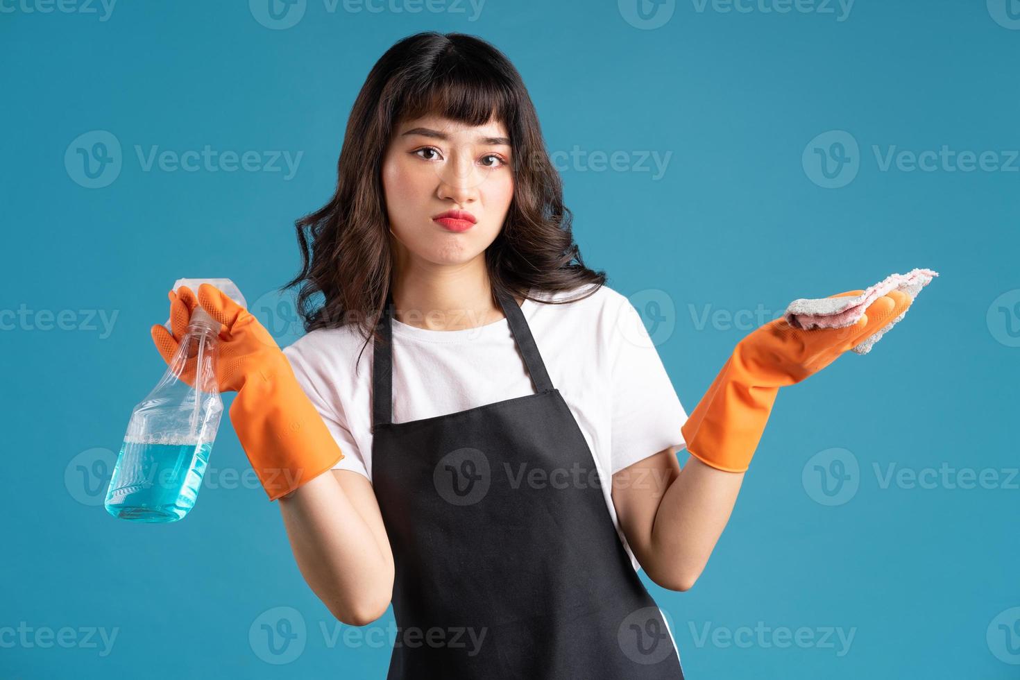 ein Foto einer asiatischen Frau in einer Schürze und Handschuhen, die sich auf den Reinigungsjob vorbereiten