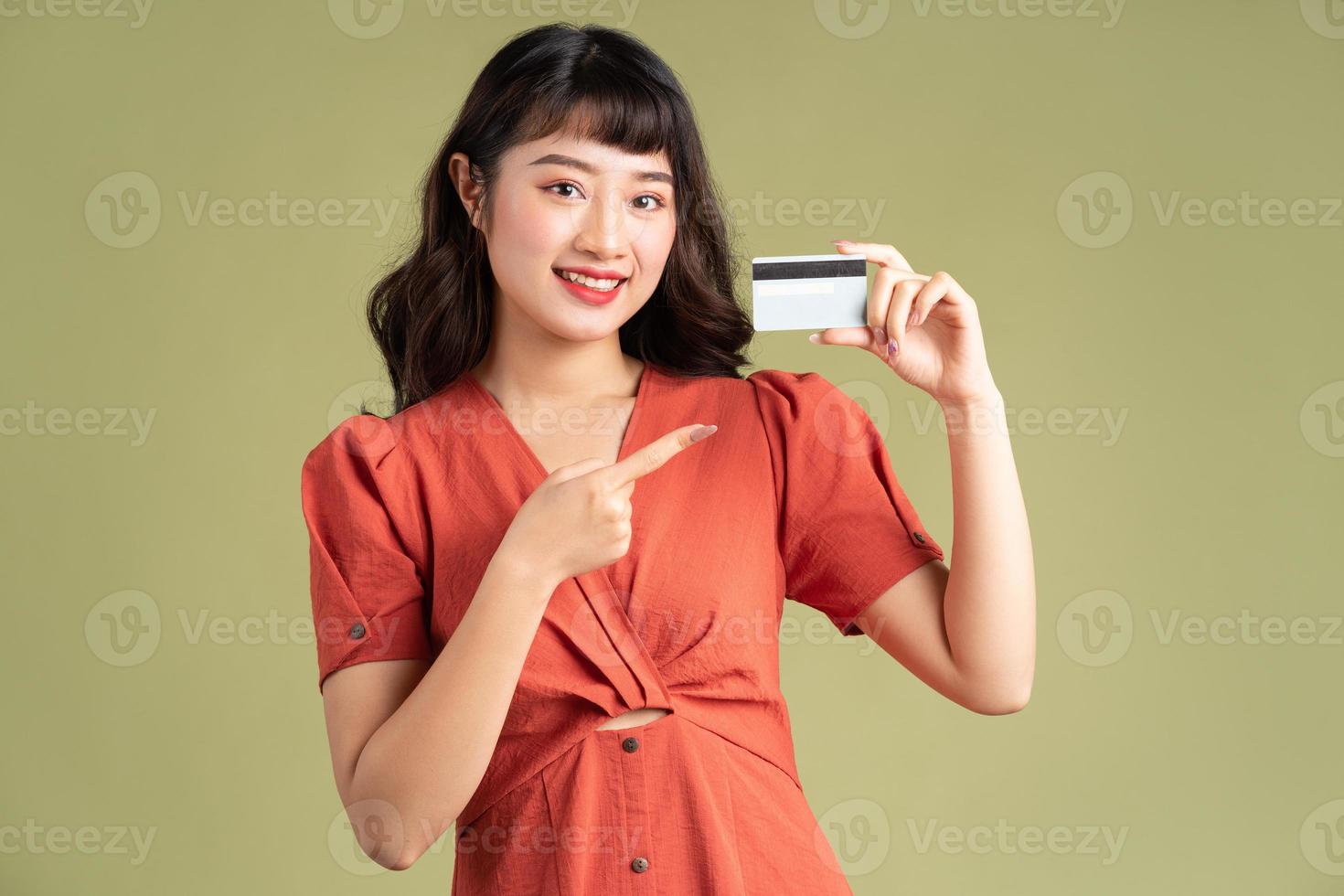 asiatische Frau, die eine Bankkarte hält und auf die Bankkarte zeigt foto