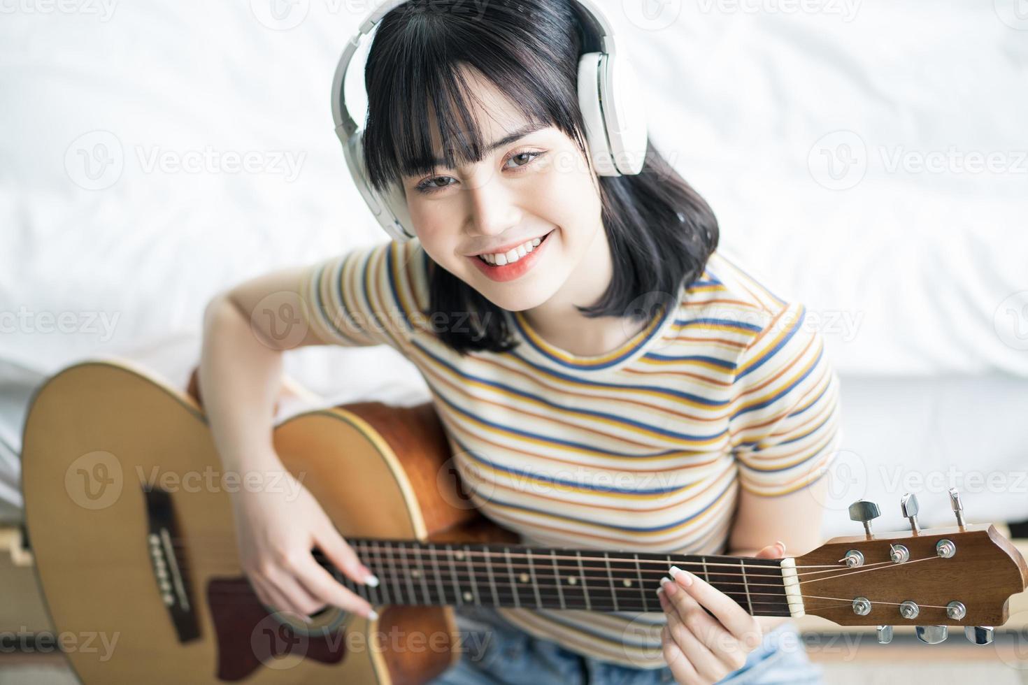 junges asiatisches mädchen übt zu hause gitarre und komponiert musik foto