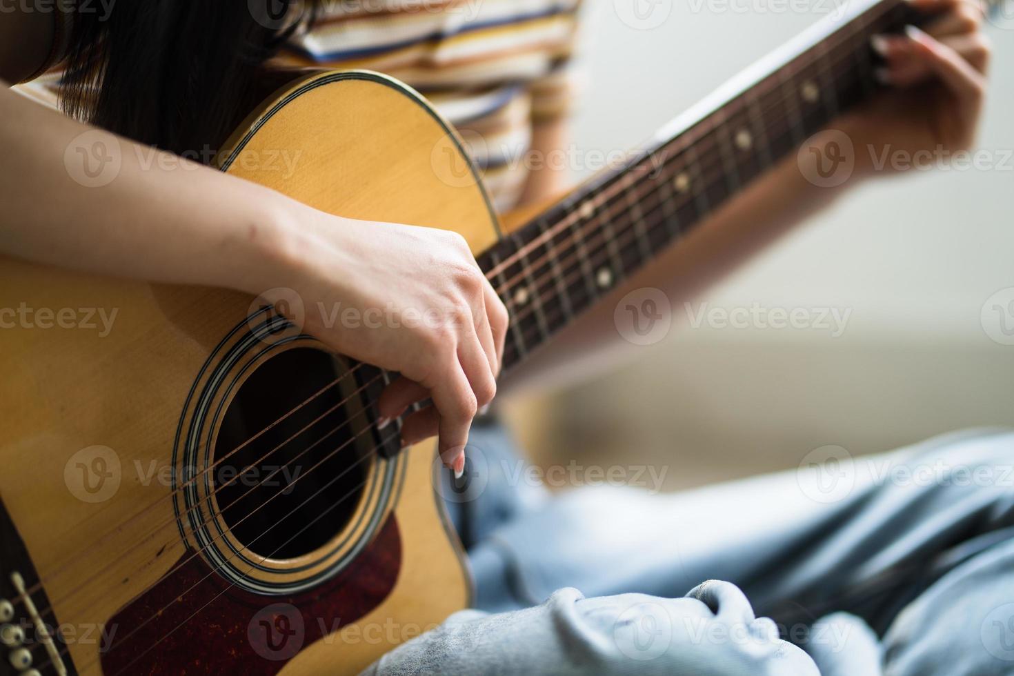 junges asiatisches mädchen übt zu hause gitarre und komponiert musik foto