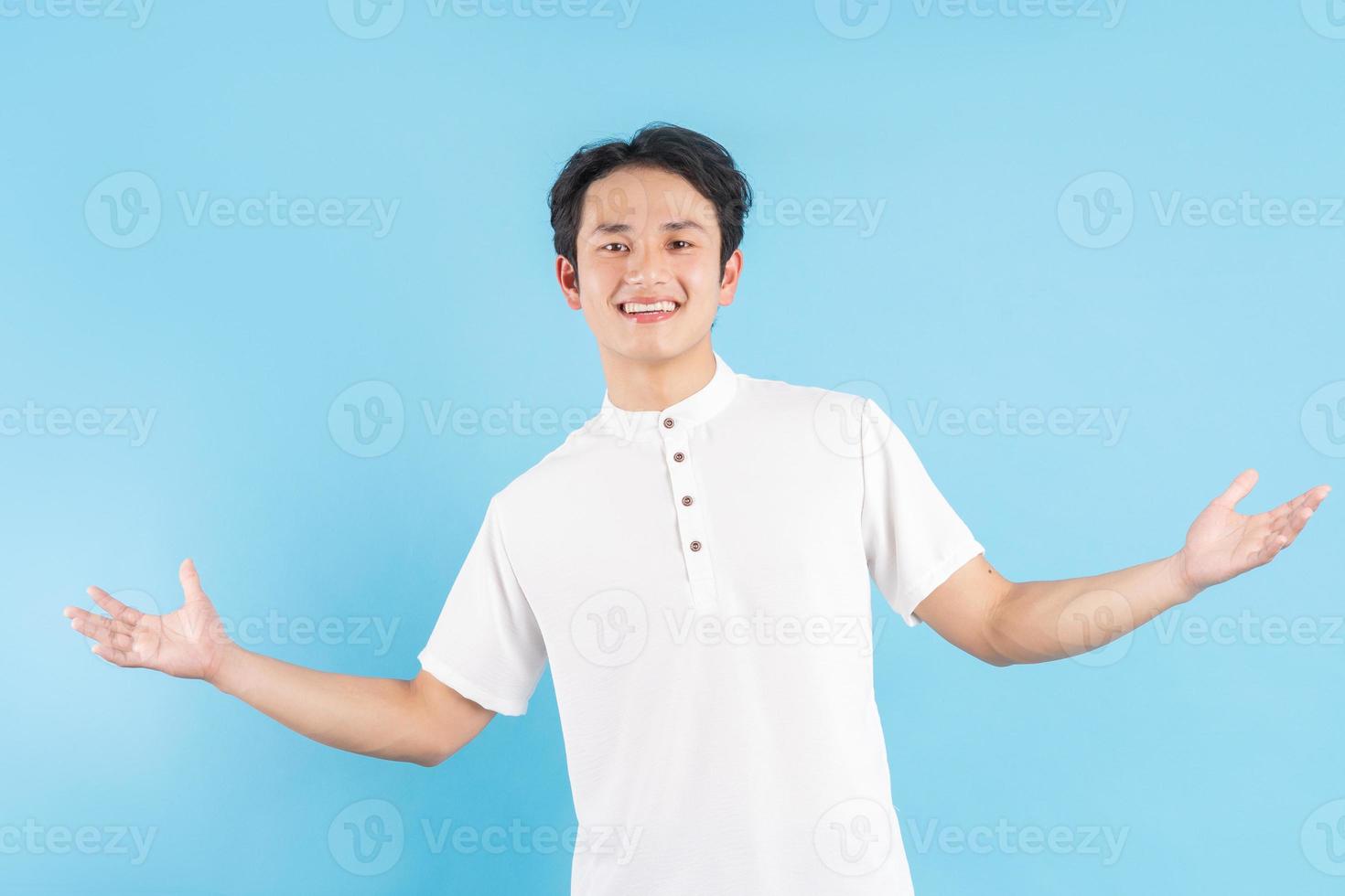 junger Mann stehend, Hände beiseite mit einem lächelnden Gesicht auf grünem Hintergrund foto