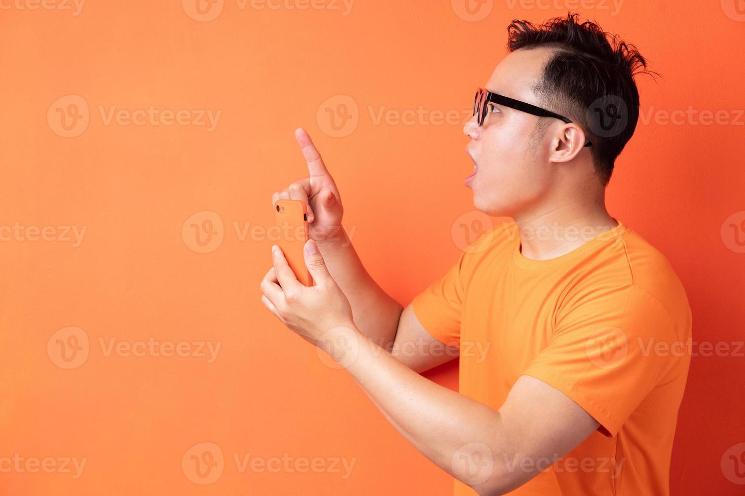 junger asiatischer mann, der das telefon mit einem überraschten ausdruck hält foto