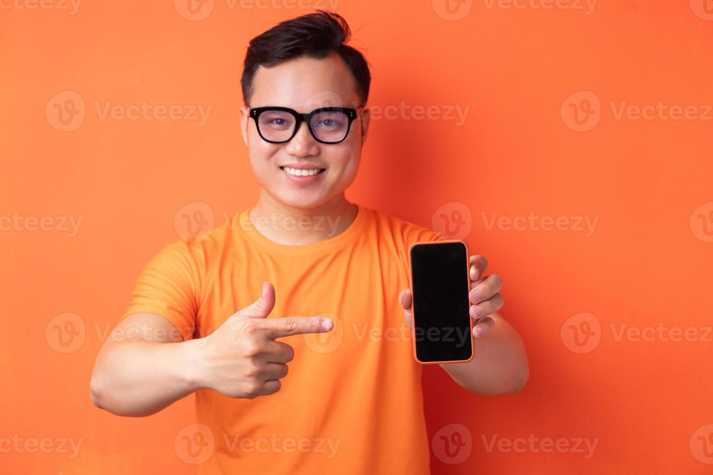 junger asiatischer mann, der das telefon mit einem aufgeregten ausdruck hält foto